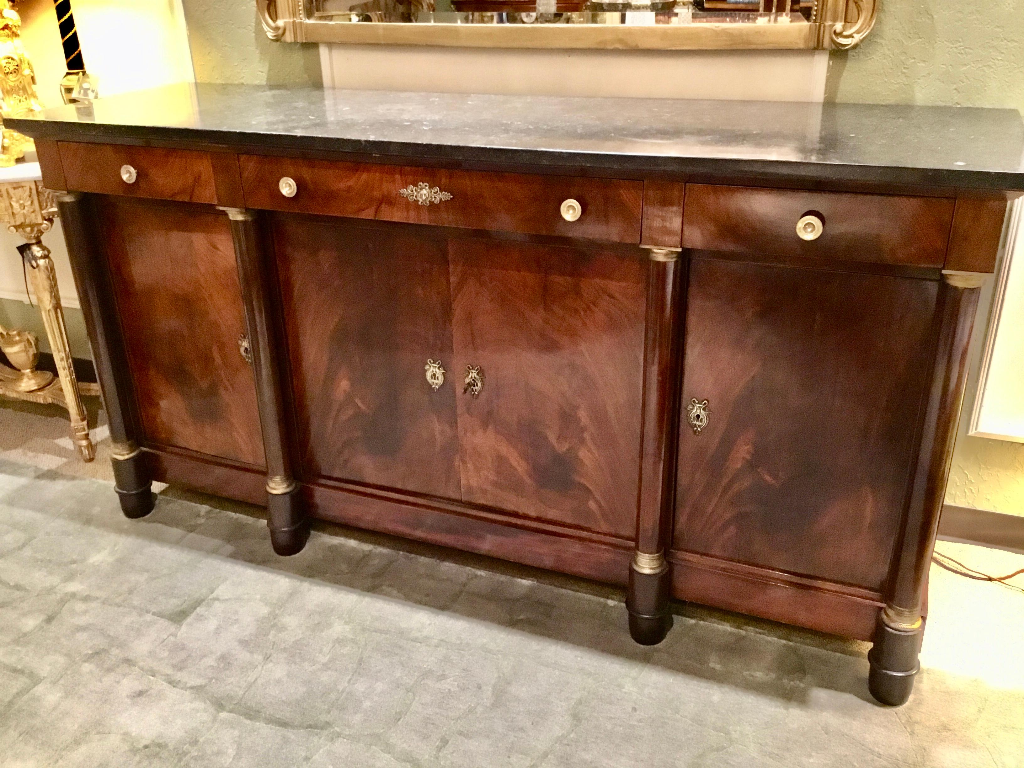 French Empire mahogany sideboard, early 20th century, fitted with three drawers, over centered
Double-door cabinet, flanked by side cabinets, interior shelf, upright columns, with gilt
Metals capitals, rising on upped feet. Black/charcoal gray