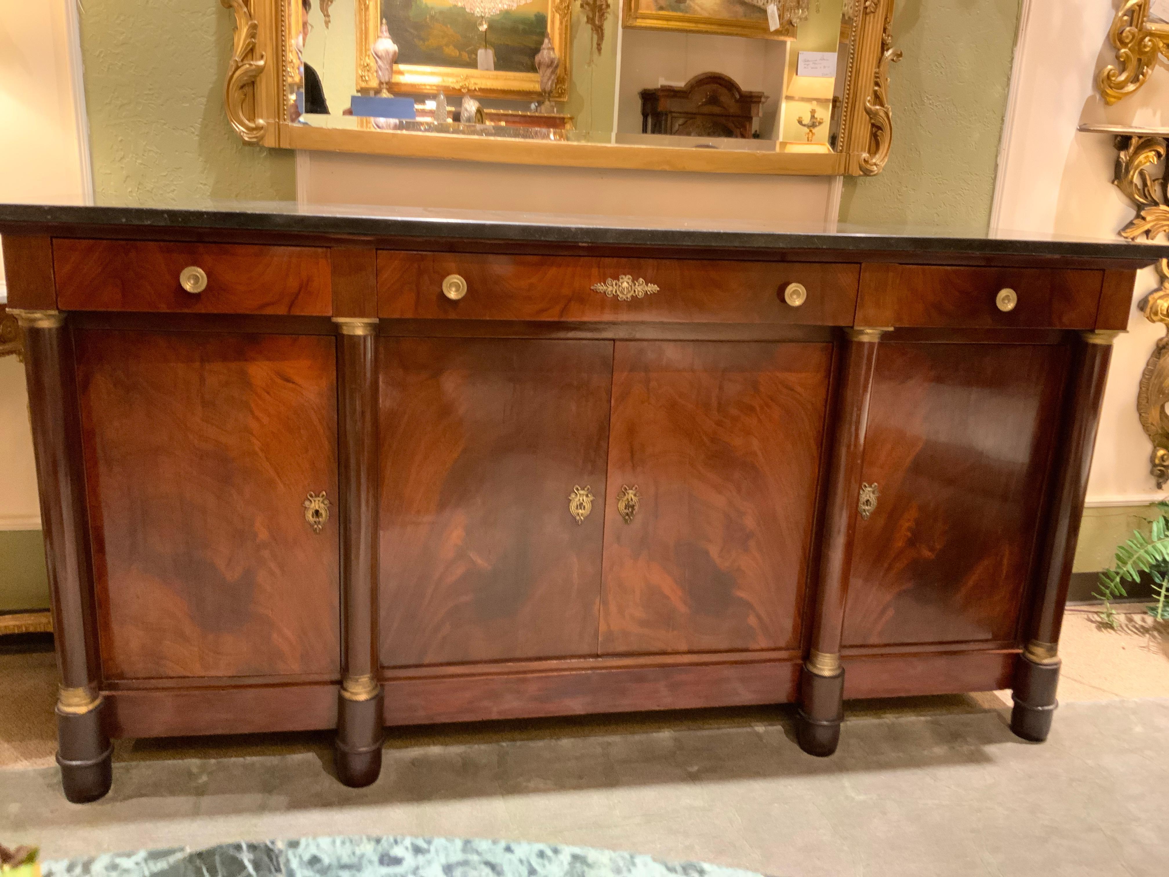 French Empire mahogany sideboard, early 20th century, fitted with three drawers, over centered
Double-door cabinet, flanked by side cabinets, interior shelf, upright columns, with gilt
Metals capitals, rising on upped feet. Black/charcoal gray