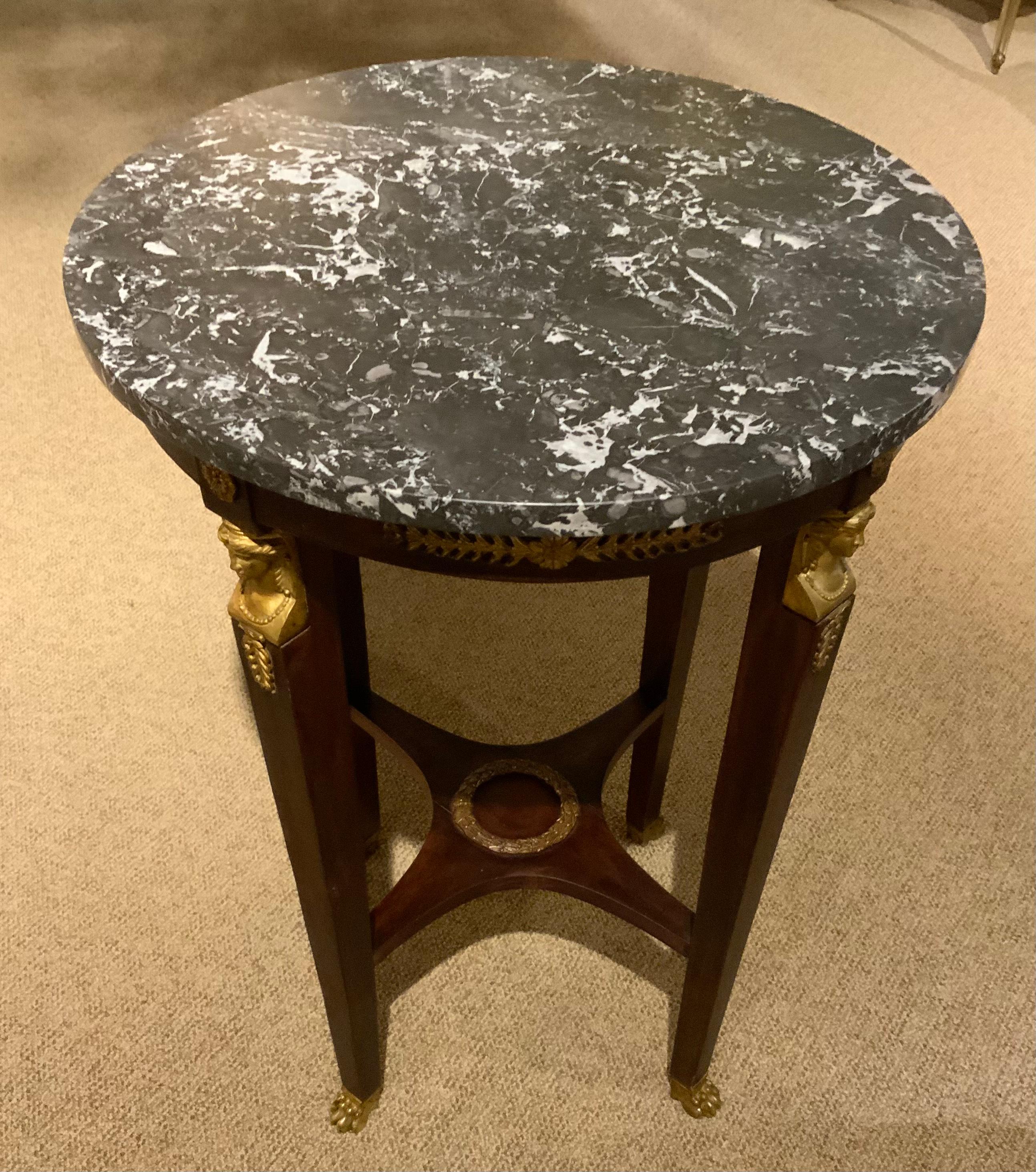 Elegant tall side table made of mahogany with black marble top. It
Is well made with exceptional bronze dore gilt mounts in the empire
Style with a tapered leg ending in bronze dore cast feet. A scrolled
Design decorates the surrounding edge of this