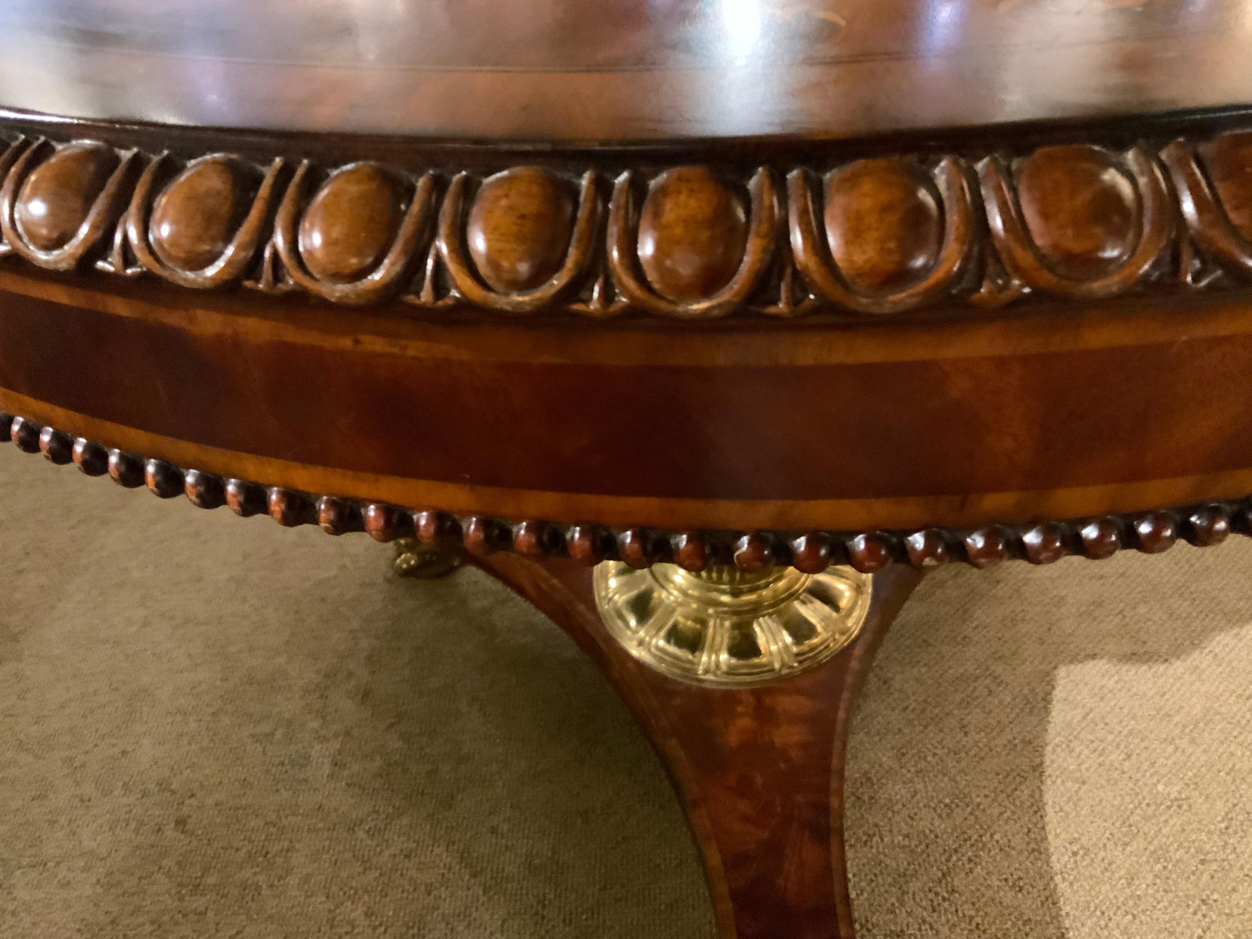 Dieser Tisch ist rund und mit einem Ei-und-Pfeil-Gadroon umrandet.
Geschnitzter Rand und feine Intarsieneinlage, getragen von einem polierten
Säule aus Bronze mit Schilfrohr, montiert auf einer dreieckigen Plattform 
Sockel mit polierten