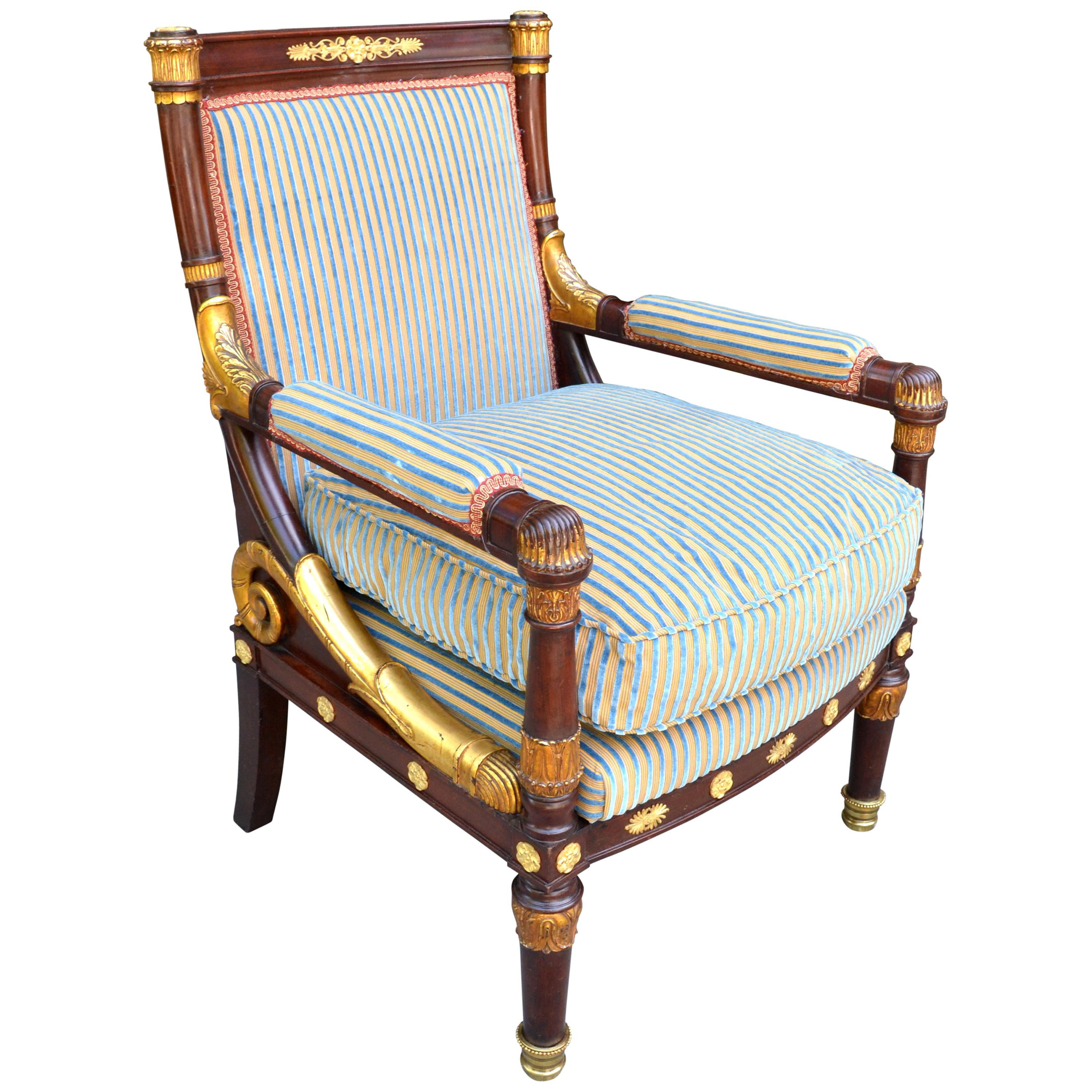 A large scale carved mahogany, gilded wood and gilt bronze mounted open armchairin the early French Empire style. The square back mahogany and giltwood frame joins the arms at the back of the chair in a downward curved gilded wood scroll joining the