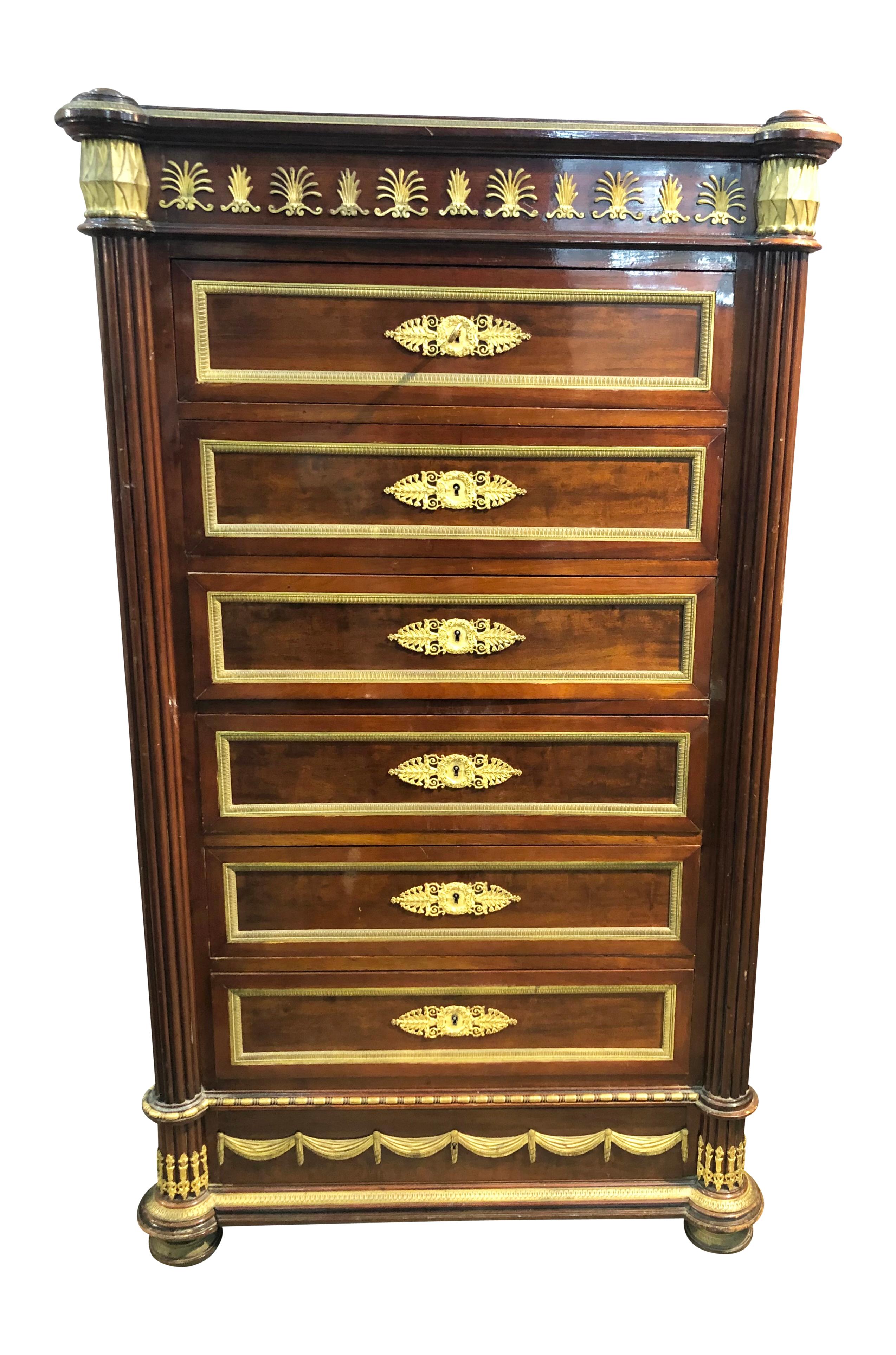 French Empire Style Ormolu Semainier tall chest of drawers. A classic French Empire style Semainier tall bedroom dresser, lingerie chest or gentleman's dresser in mahogany and bronze ormolu with seven drawers. This magnificent piece is framed with