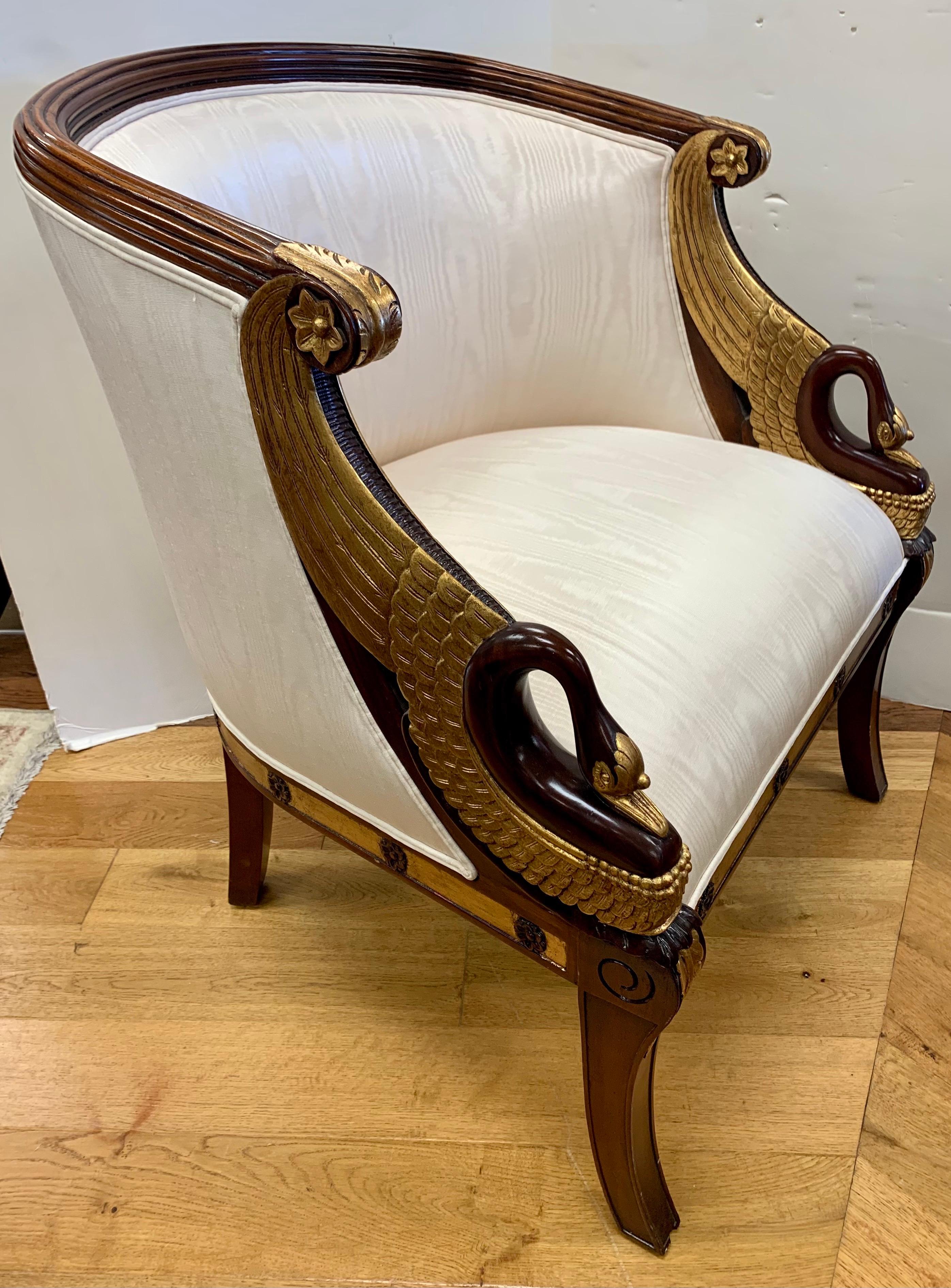 Elegant French empire style carved mahogany barrel back chair with exquisite gold details and the most magnificent gold swans on both of the arms! Upholstered in a cream silk fabric.