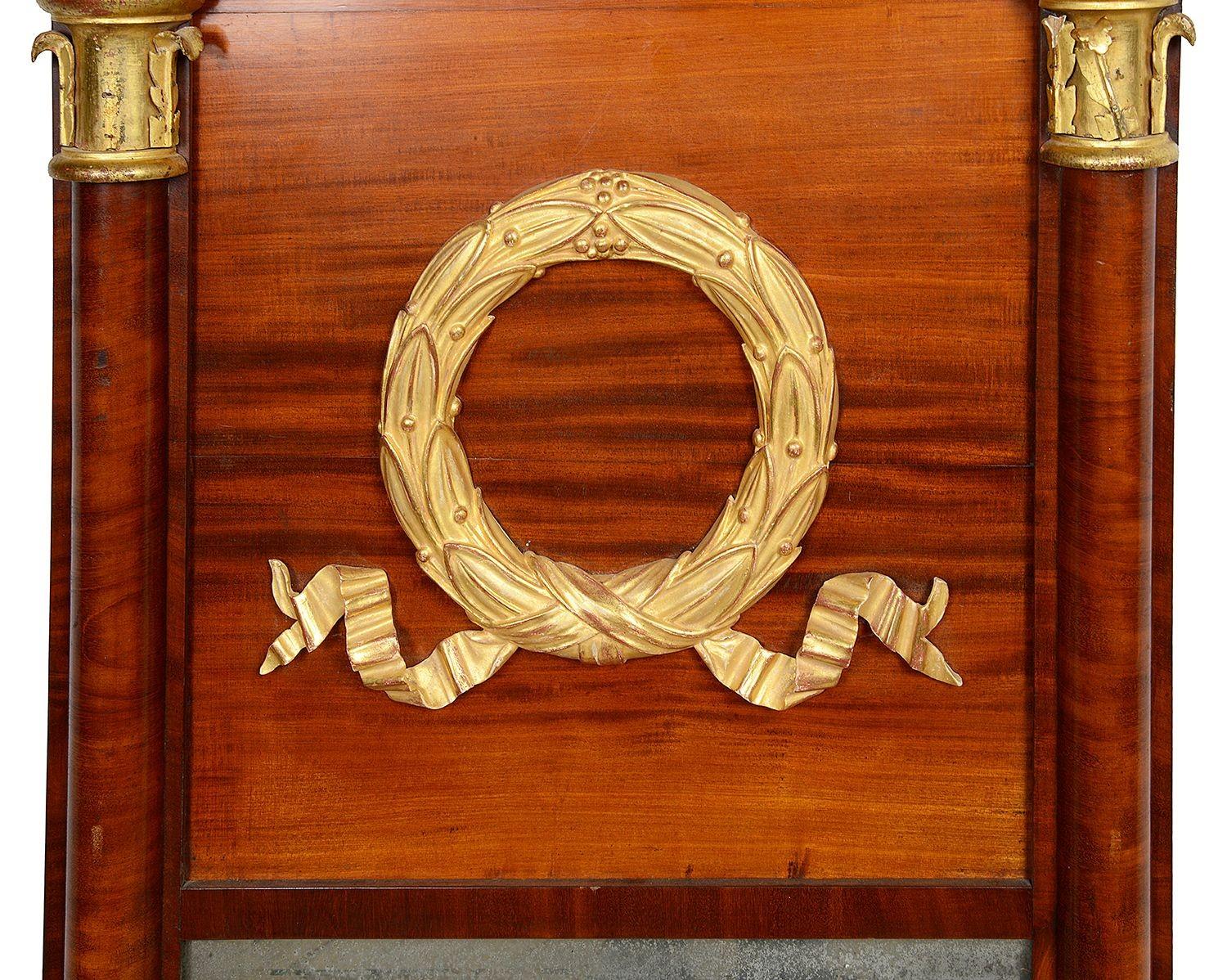 Elegante specchio da parete in mogano in stile Impero francese del 19° secolo, con splendide decorazioni classiche intagliate in legno dorato a forma di corona e nastro. Modanature e colonne Gadroon su entrambi i lati e piastra a specchio Mercury