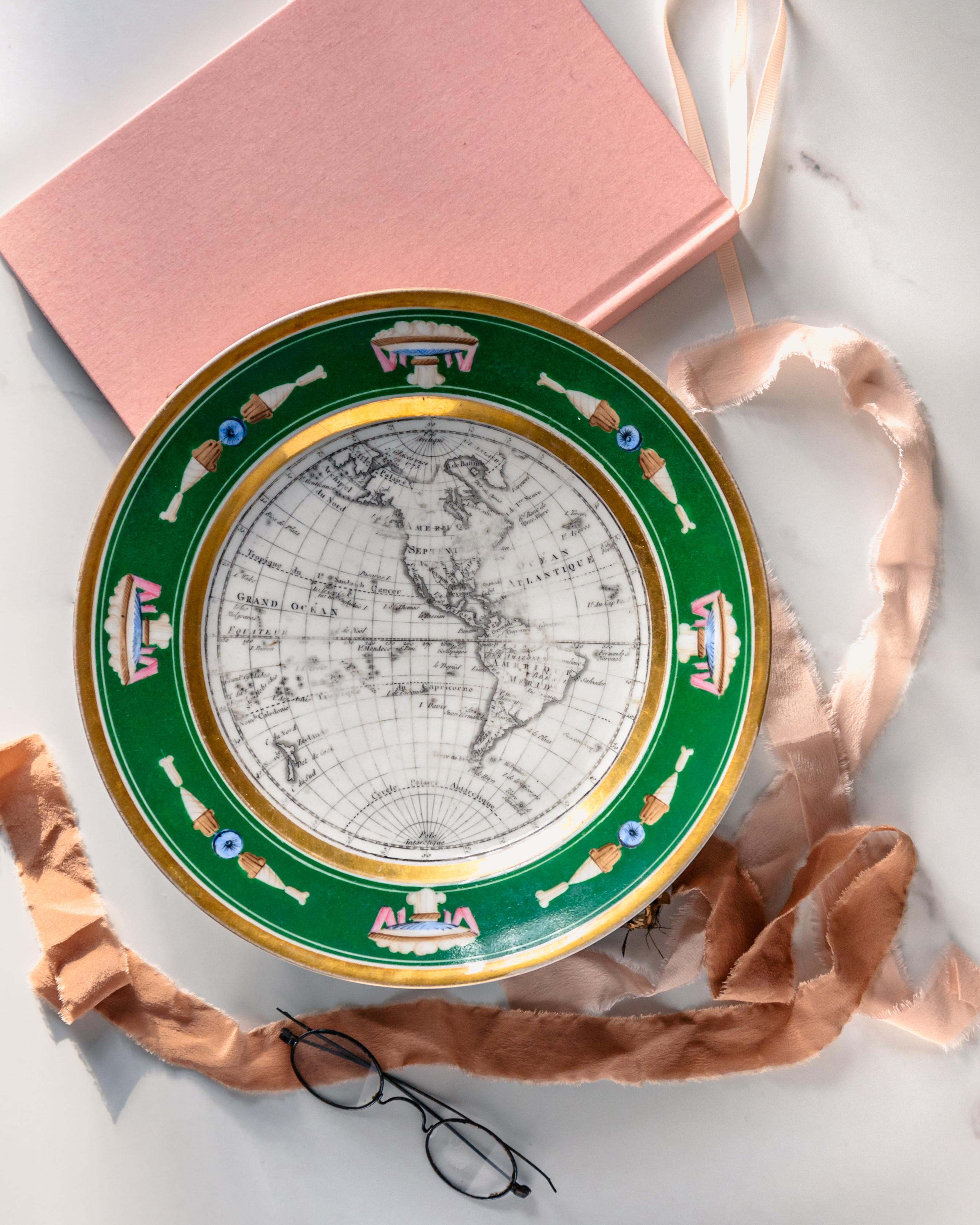 Ein schöner kartografischer Kabinettteller aus Porzellan im französischen Empire-Stil aus der Zeit um 1825 mit einer Karte von Nordamerika, die mit einer apfelgrünen und vergoldeten Bordüre mit neoklassizistischen Motiven verziert ist.

Dieser
