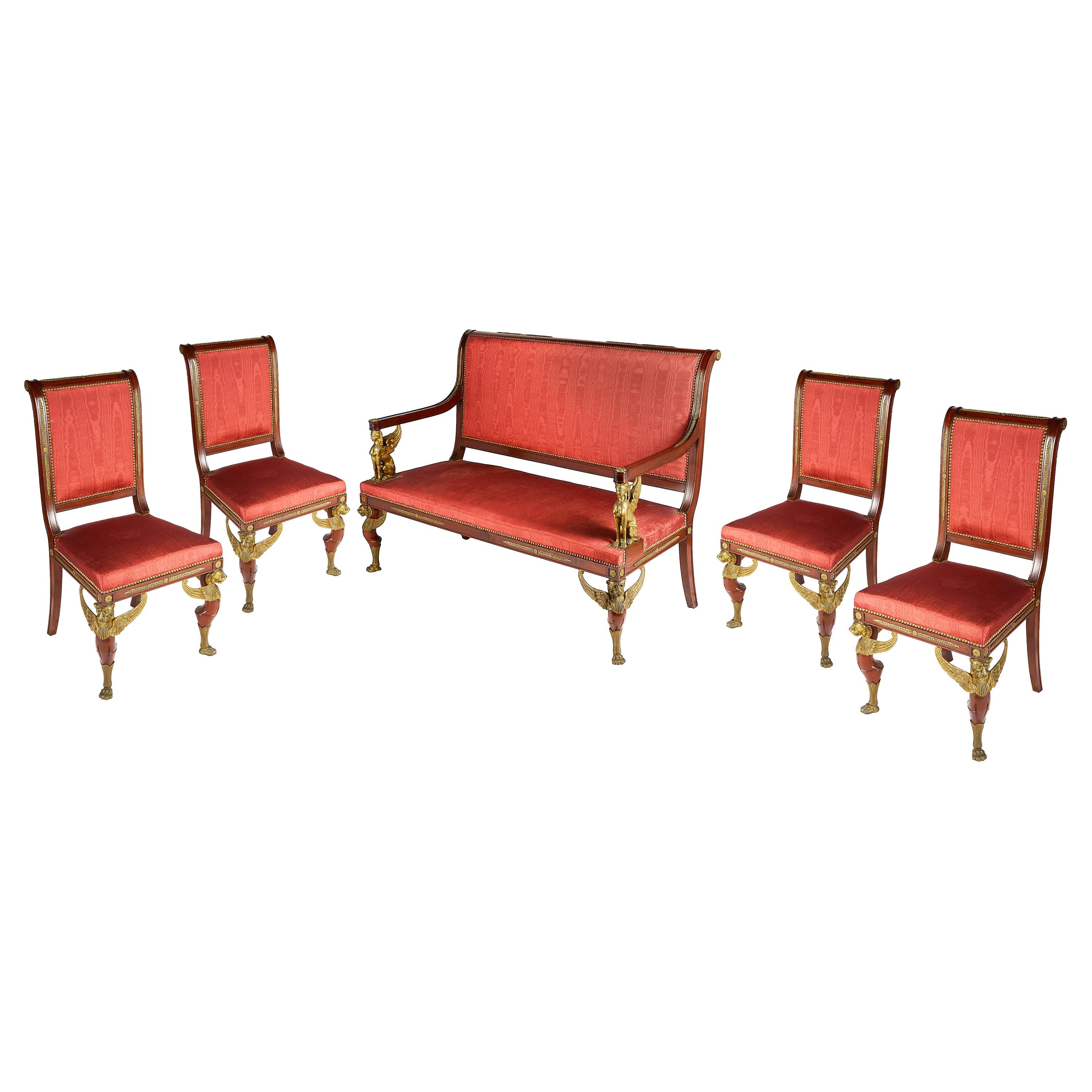 A good quality late 19th century French mahogany Empire influenced three piece salon suite, consisting on a two-seat sofa and two side chairs, each with gilded monopodia mounts.