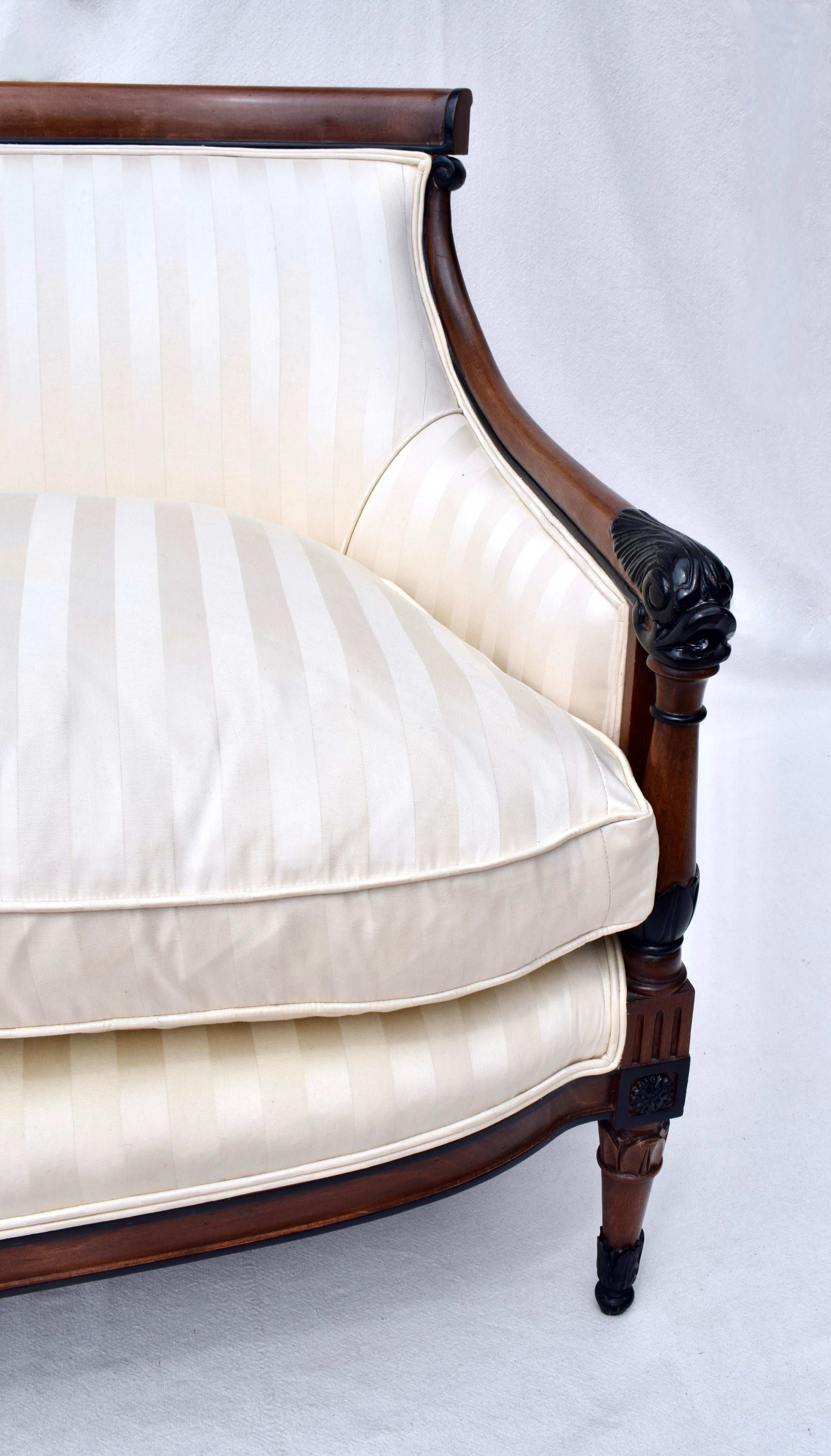 A small scale sofa in the French Empire style featuring exquisite curved Mahogany frame embellished with intricate carvings & turnings throughout.  The sofa was reupholstered in 2020 boasting a plush Down feather loose seat cushion. Very clean
