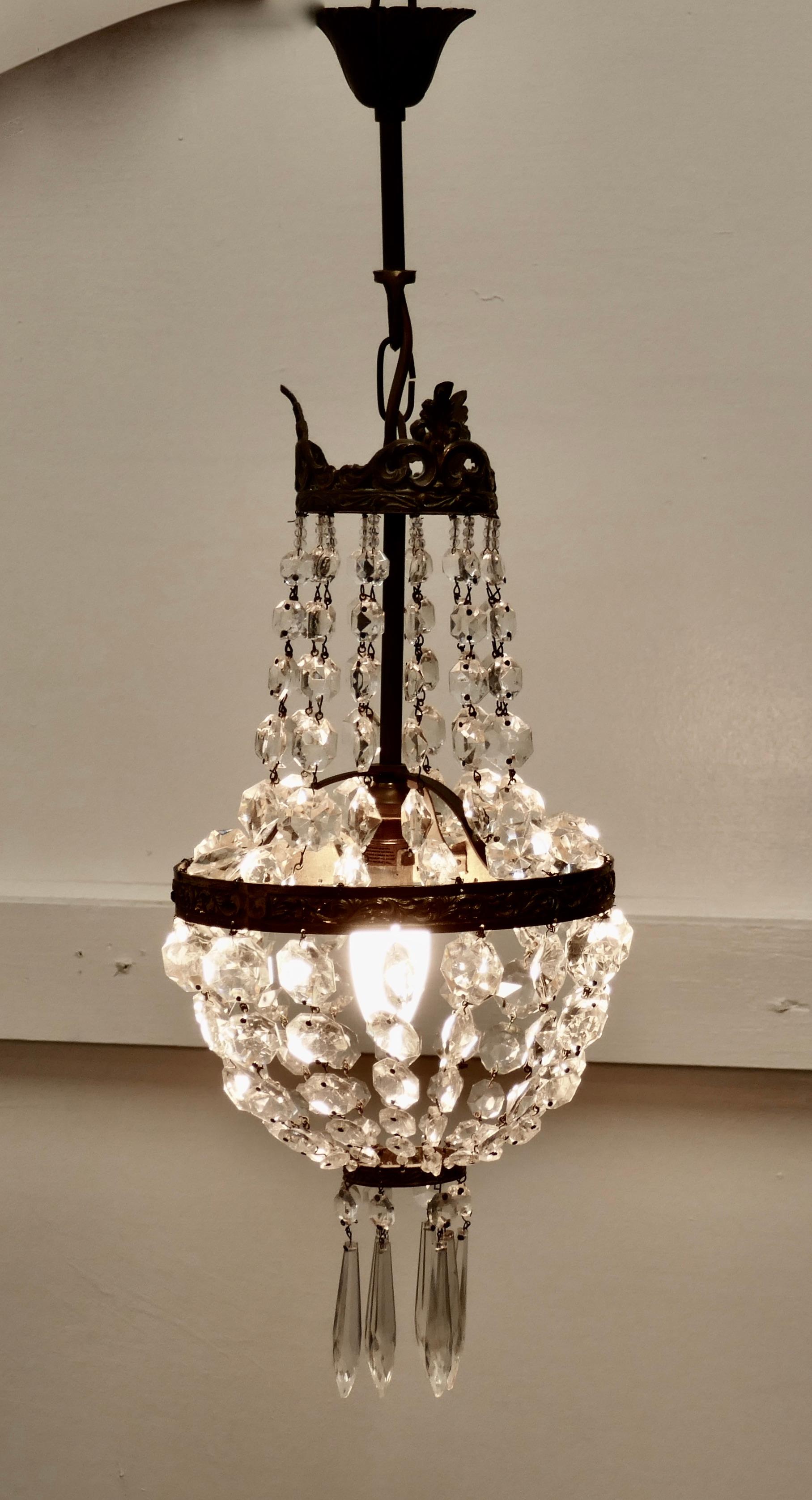French Empire style tent chandelier

This is a lovely piece especially where a very large chandelier is not possible, it has an aged brass crown hung with chains of cut crystal beads, completed at the bottom with a basket of crystal drops hung