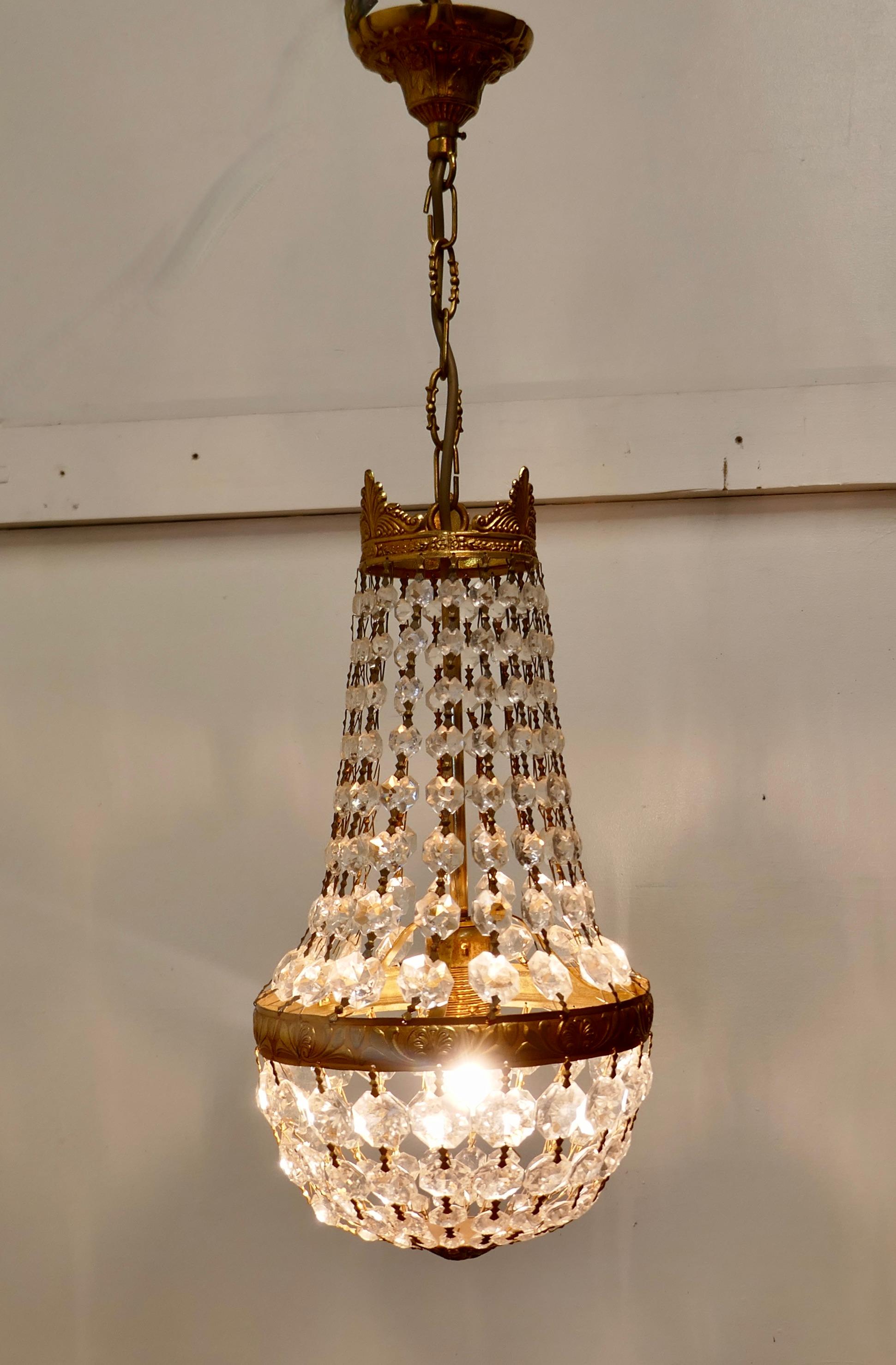 French Empire Style Tent Chandelier

This is a lovely piece especially where a very large chandelier is not possible, it has a bright brass crown hung with chains of cut crystal beads, completed at the bottom with a basket of crystal drops 

The