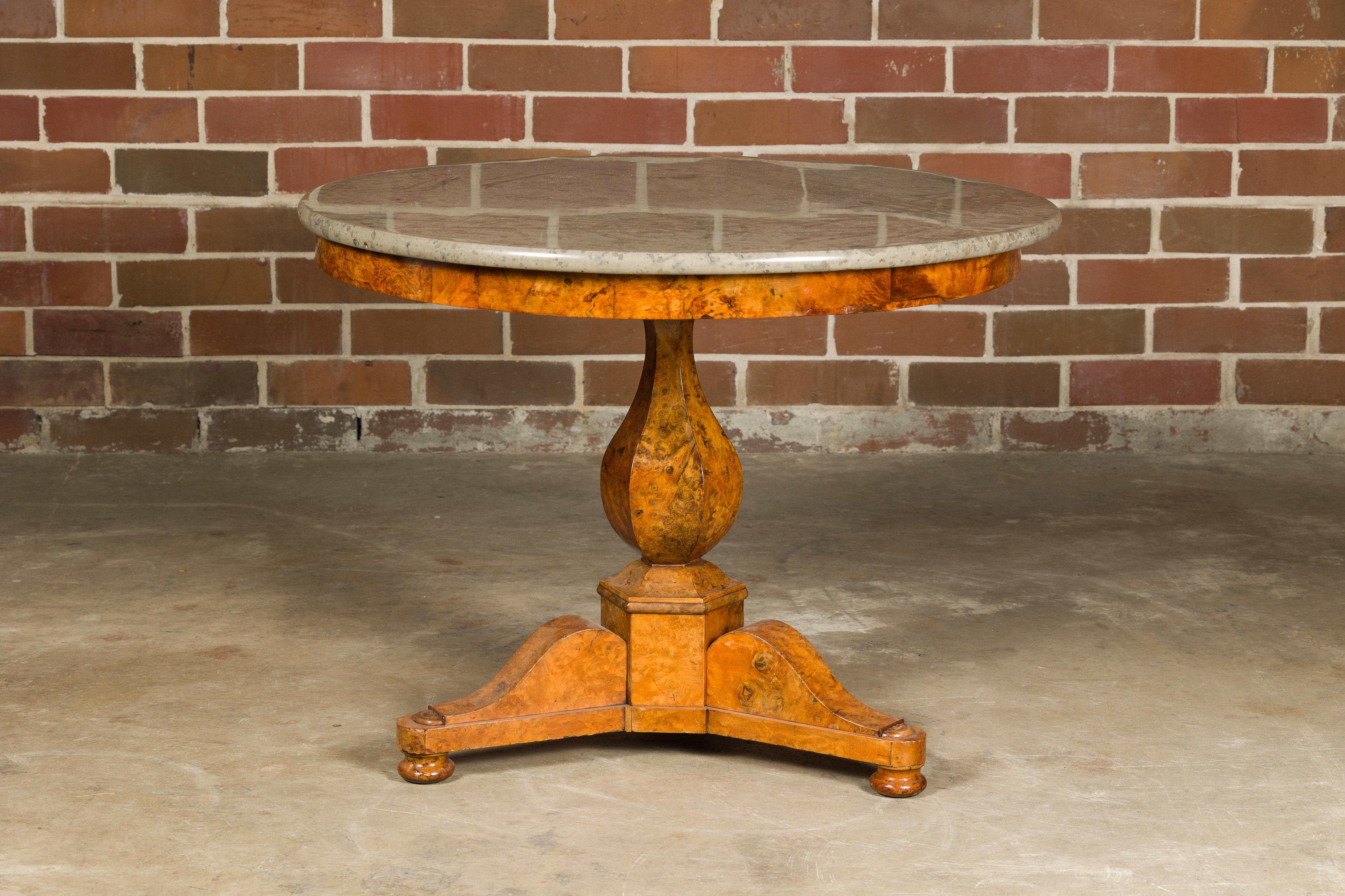 A French Empire period walnut table from the 19th century with circular marble top, pedestal and tripod base. Evoke the elegance of 19th-century France with this resplendent French Empire period walnut table. This masterpiece is a blend of artistry
