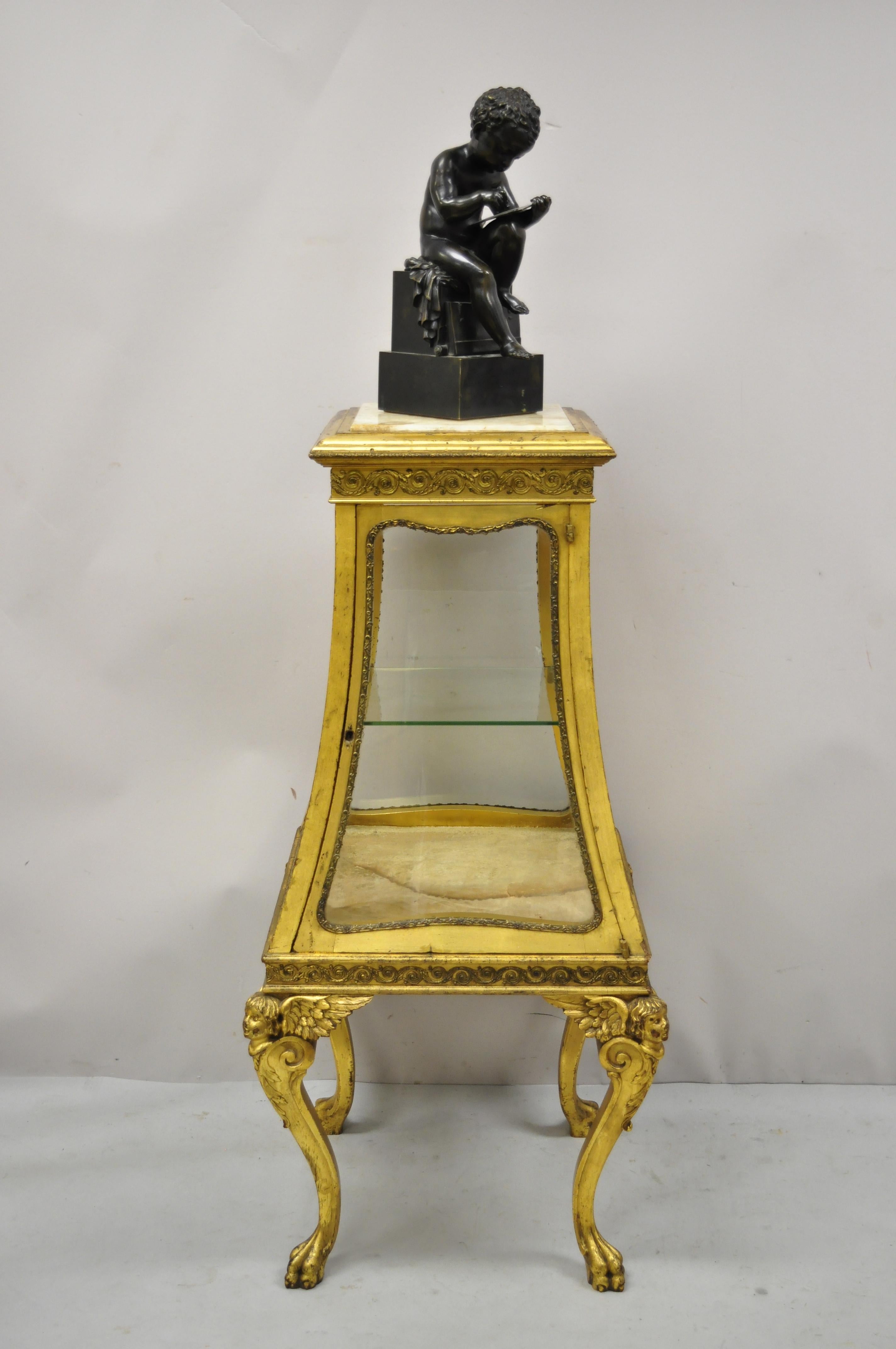 Antique 19th century French empire winged cherub gold gilt vitrine curio display cabinet pedestal with onyx top. Item features onyx stone top, angel/cherub legs with wings, paw feet, distressed gold gilt finish, glass on all sides, 1 swing door, no