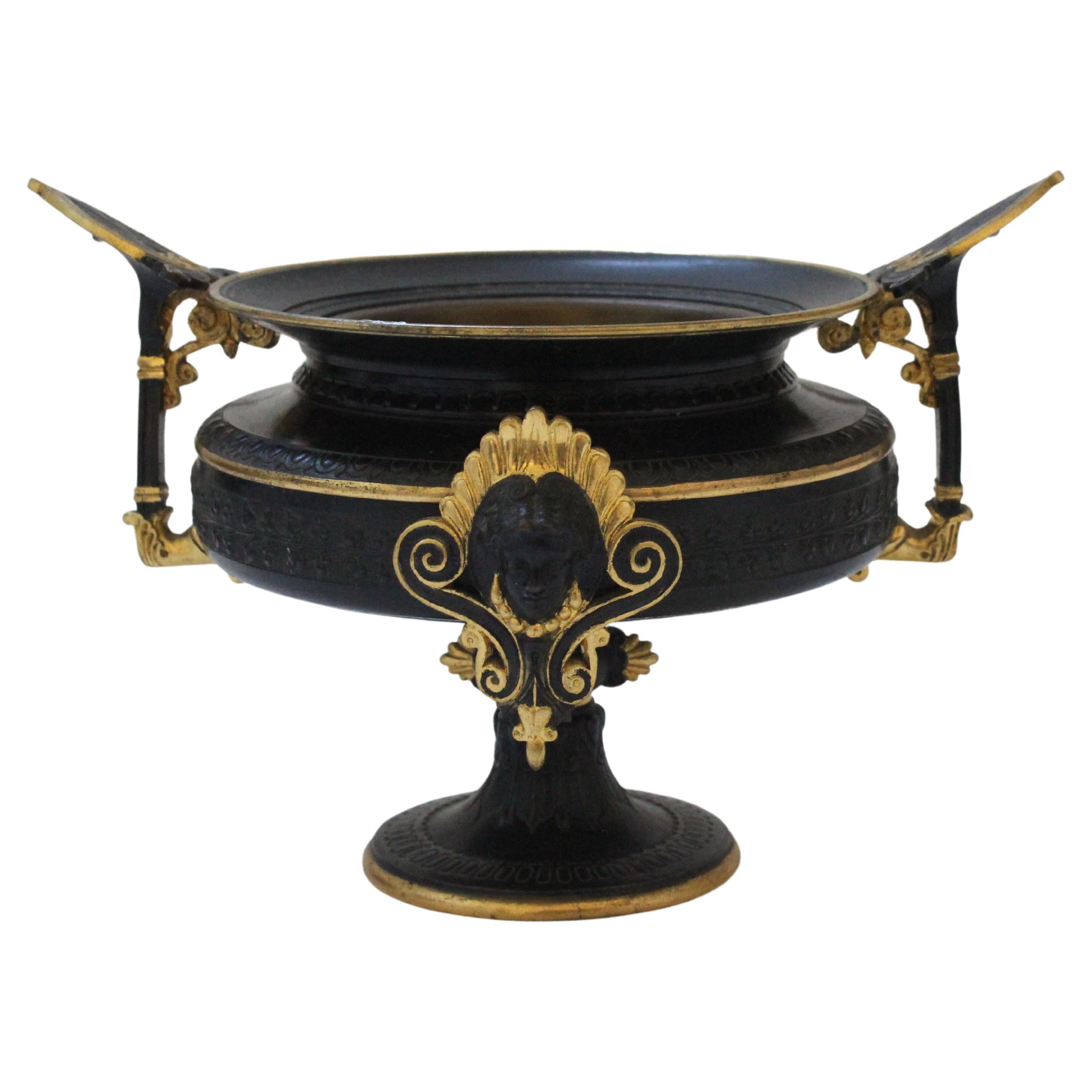 This stylish and chic Etruscian revival compote dates between 1860s-1890s and was acquired in France. The piece is fabricated in gilded and patinated bronze, and detailed with stylized palmettos, trailing foliage, and female face cartouches.