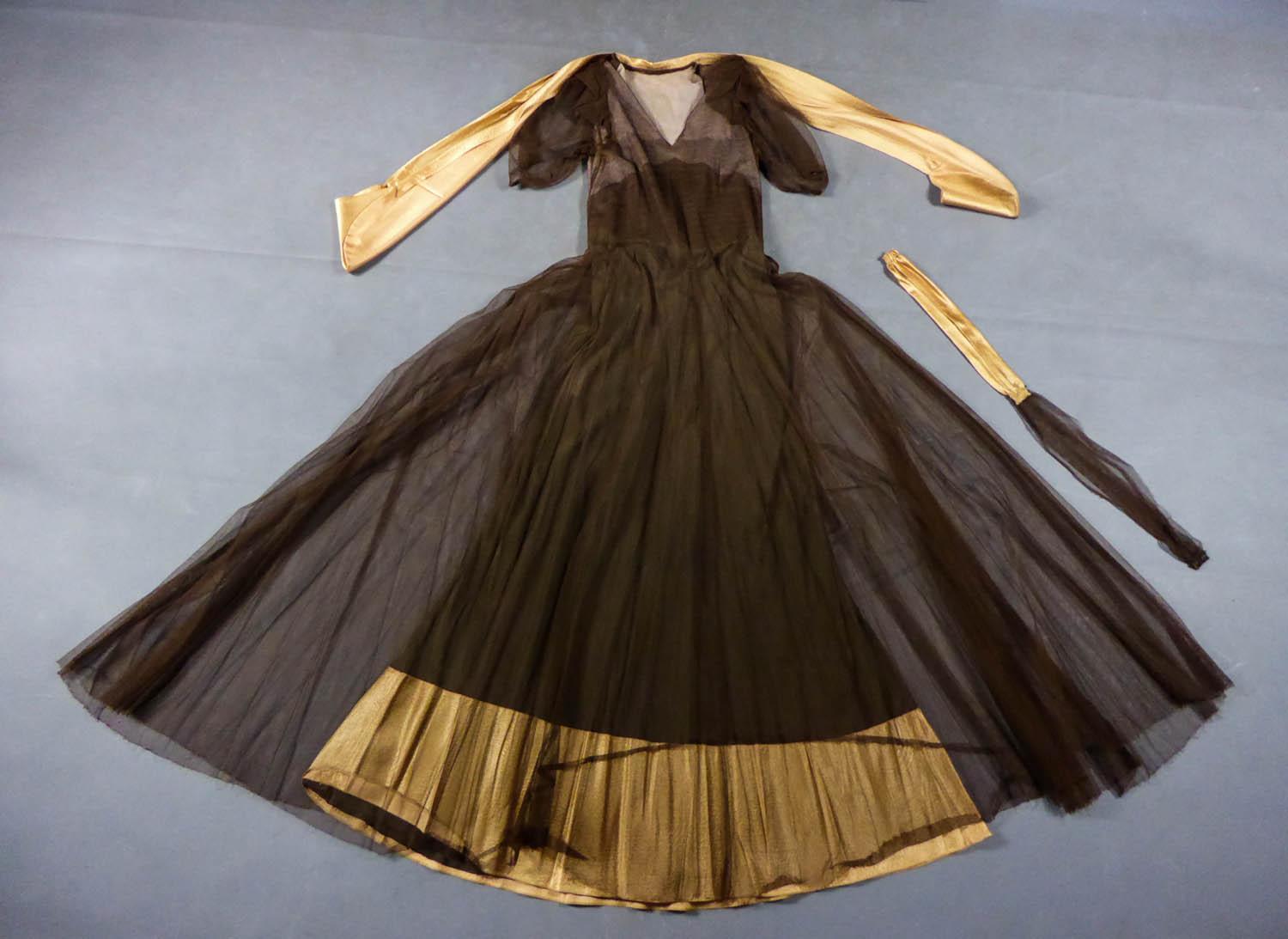 Circa 1930/1940
France

Elegant long evening dress, collector's item, in cotton tulle and gold goffered satin with skin effect dating from the 1930s. Interesting structure with transparency effect: built-in under-dress in brown silk crepe with