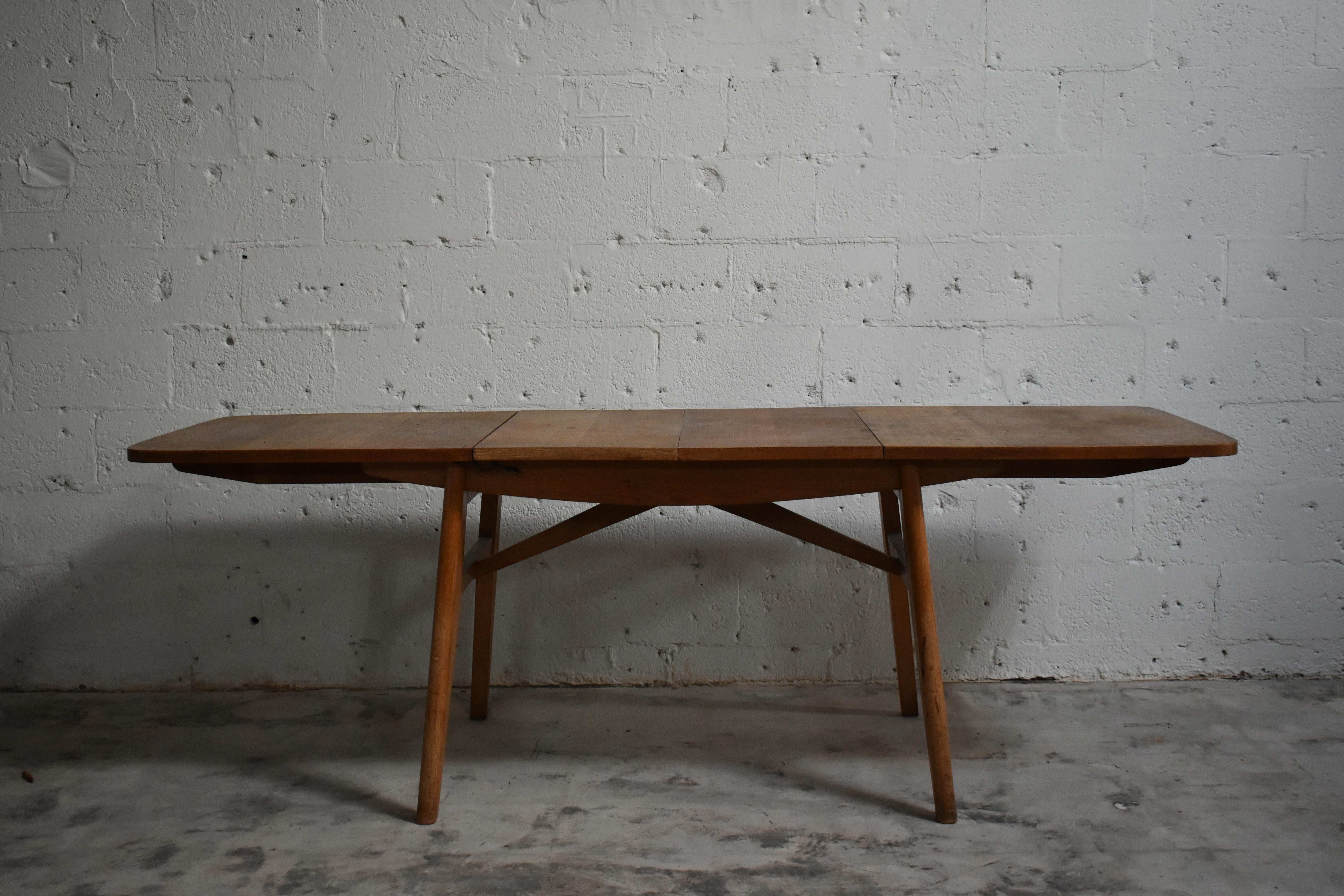 Une table de salle à manger à rallonge en chêne chaleureux à la silhouette épurée et fonctionnelle. Les coins doucement arrondis et les pieds fuselés lui confèrent un attrait mid-century, tandis que le grain figuré sur le dessus lui confère un