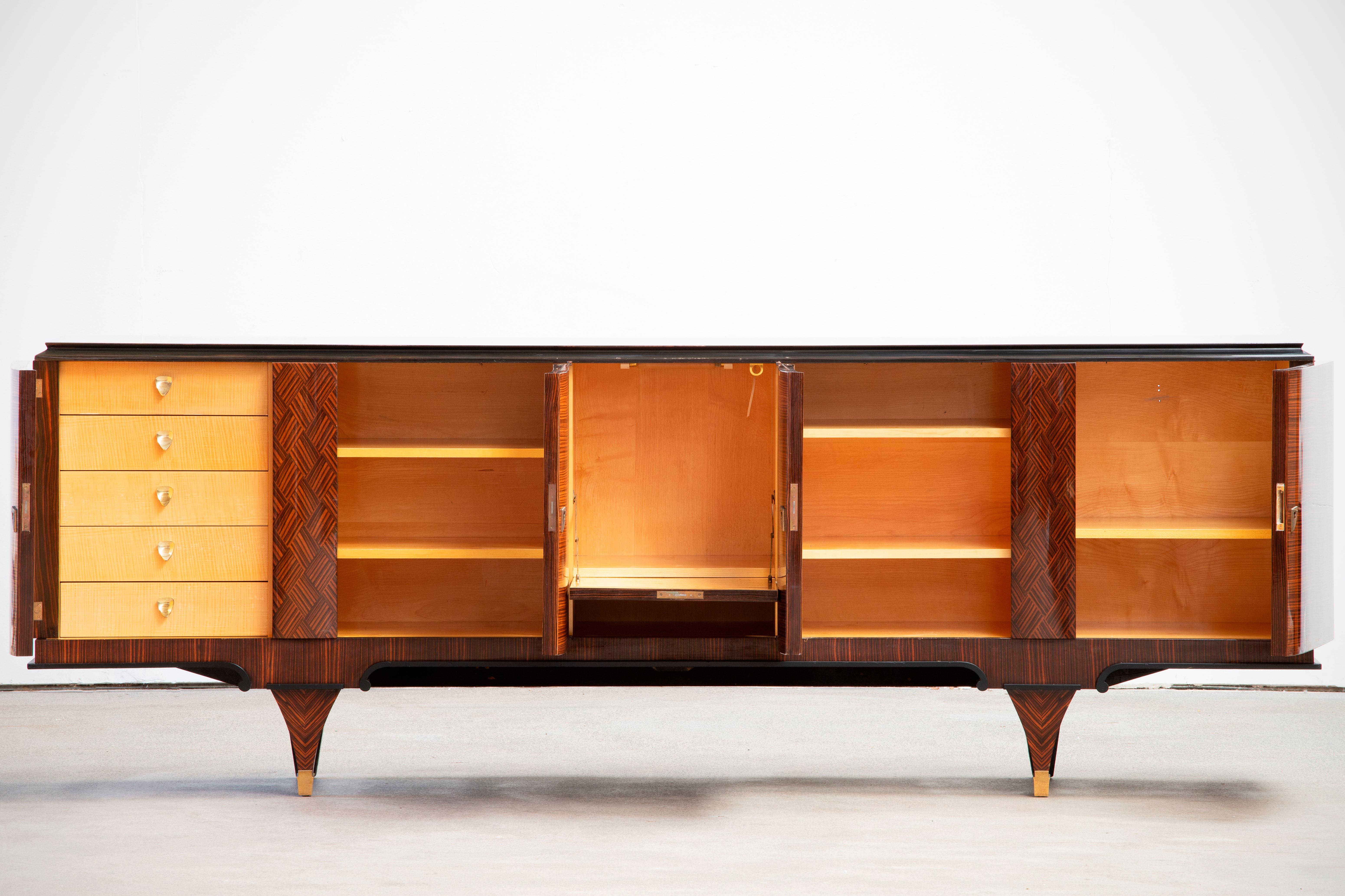 French Art Deco sideboard, credenza, with bar cabinet. The sideboard features stunning Macassar wood grain and rich pattern. It offers ample storage, with shelves, drinks cabinet and a column of drawers. The case rests on tall tapered legs. A unique