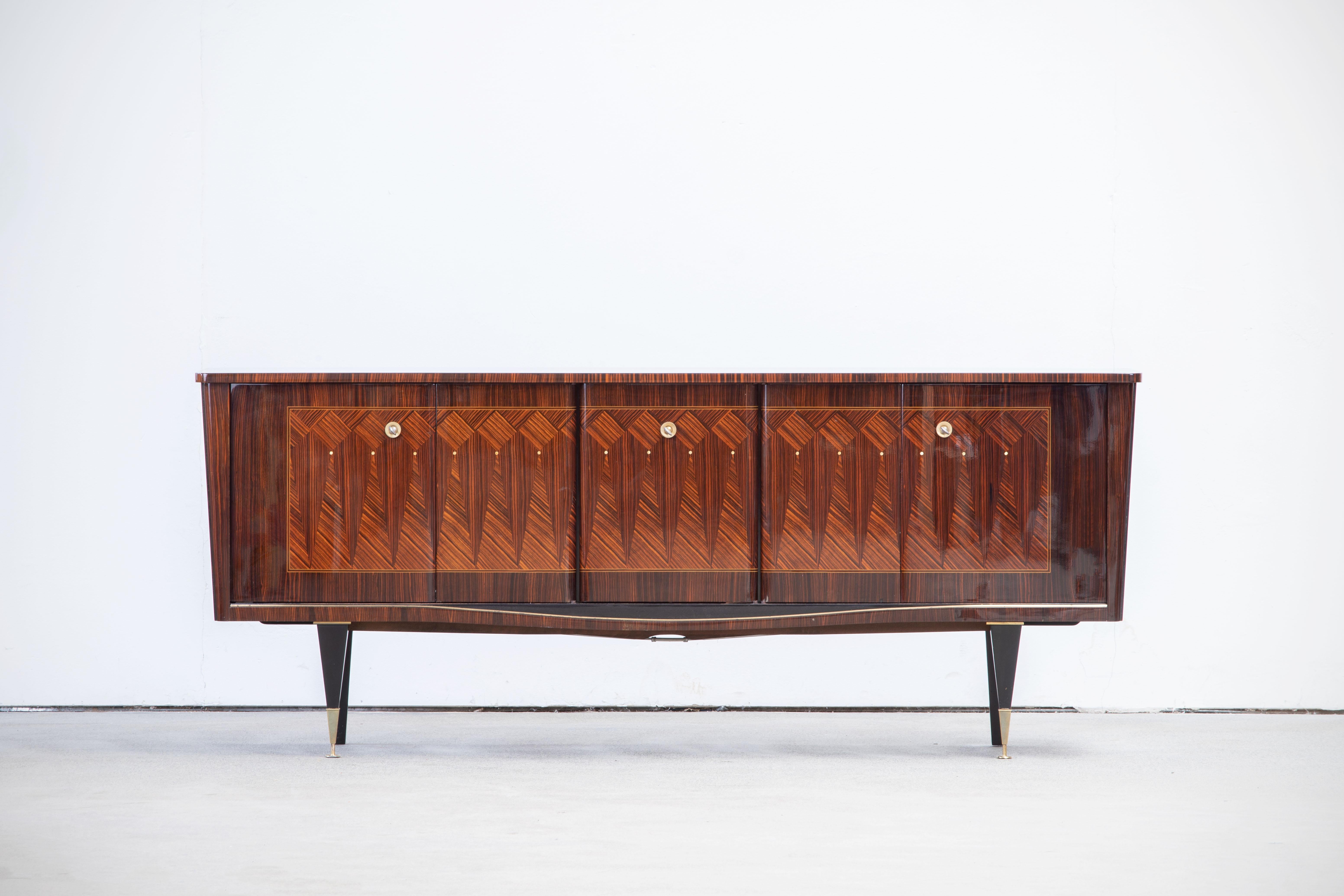 French Art Deco sideboard, credenza, with bar cabinet. The sideboard features stunning Macassar wood grain and rich pattern. It offers ample storage, with shelves and a column of drawers. The case rests on tall tapered legs. A unique blend of Art