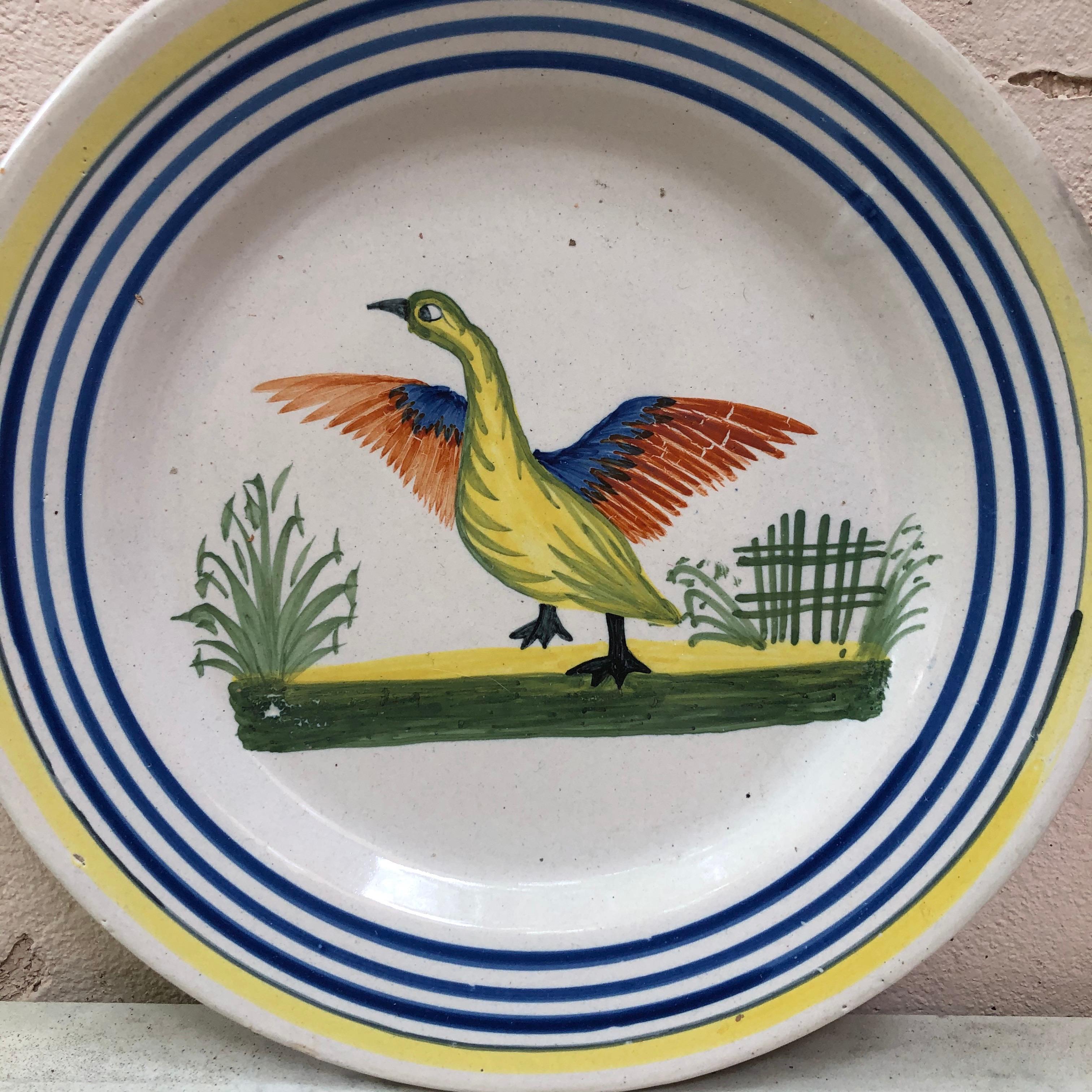 Une grande assiette en faïence française avec un oiseau signée Henriot Quimper, vers 1950.
Bordure jaune colorée et lignes bleues.
Mesure : 9,5