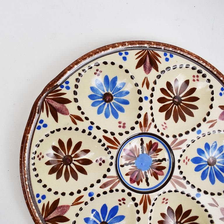 A beautiful faience oyster plate by HB Quimper. This lovely serving piece features hand painted flowers in blue and deep almost maroon red. Each flower is painted alternately at the center of each of the 6 oyster wells. A well in the center features