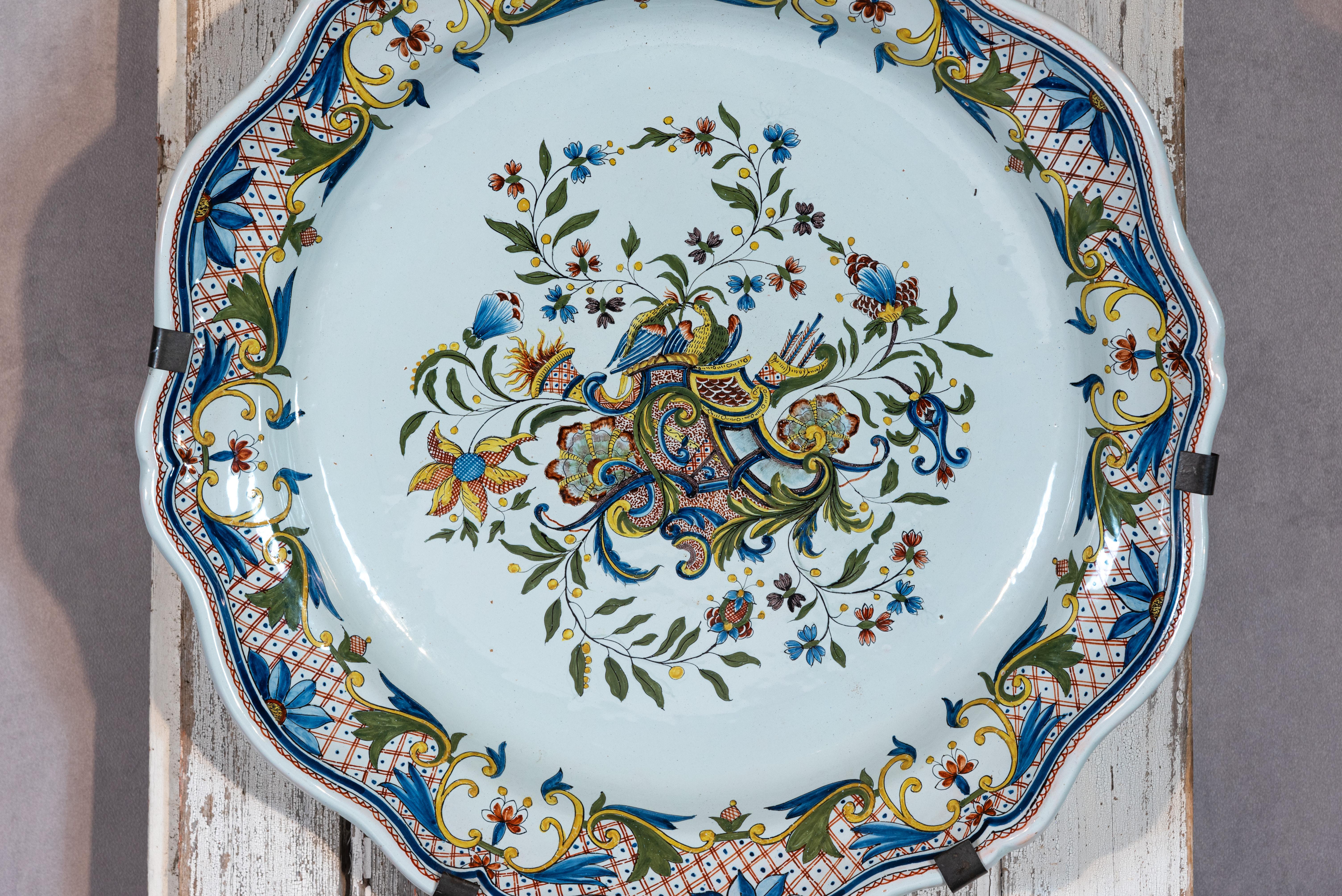 Bringen Sie einen Hauch von französischem Charme in Ihr Zuhause mit dieser schönen französischen Fayence-Quimper-Platte. Diese Platte mit ihren wunderschönen floralen Ornamenten im Inneren und um den Teller herum ist ein Beweis für die