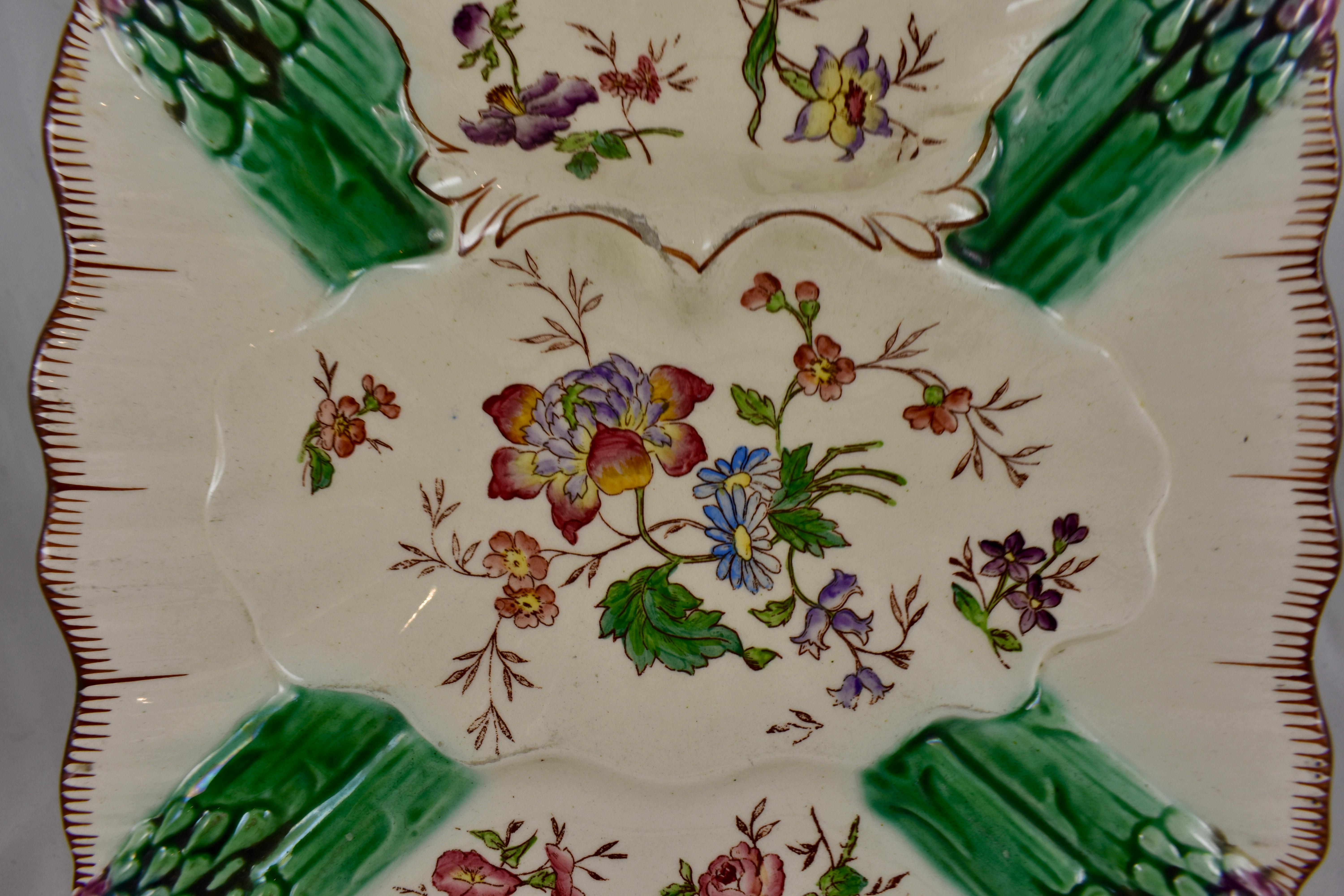 A French earthenware, hand painted square asparagus plate, circa 1890-1910.

A pair of Majolica glazed asparagus tips are shown at each corner. Floral sprays are strewn across the front of a mold with a deep sauce well. The rim shows a painted