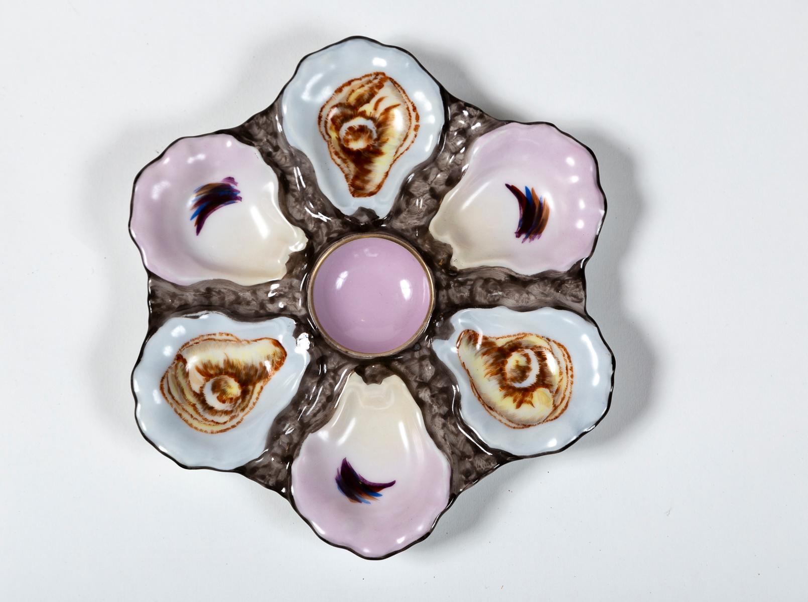 Plato de ostras de loza francesa, finales del siglo XIX. De porcelana pintada a mano, con seis pocillos en forma de concha de ostra. Bellamente pintado con un pozo central de color lavanda.