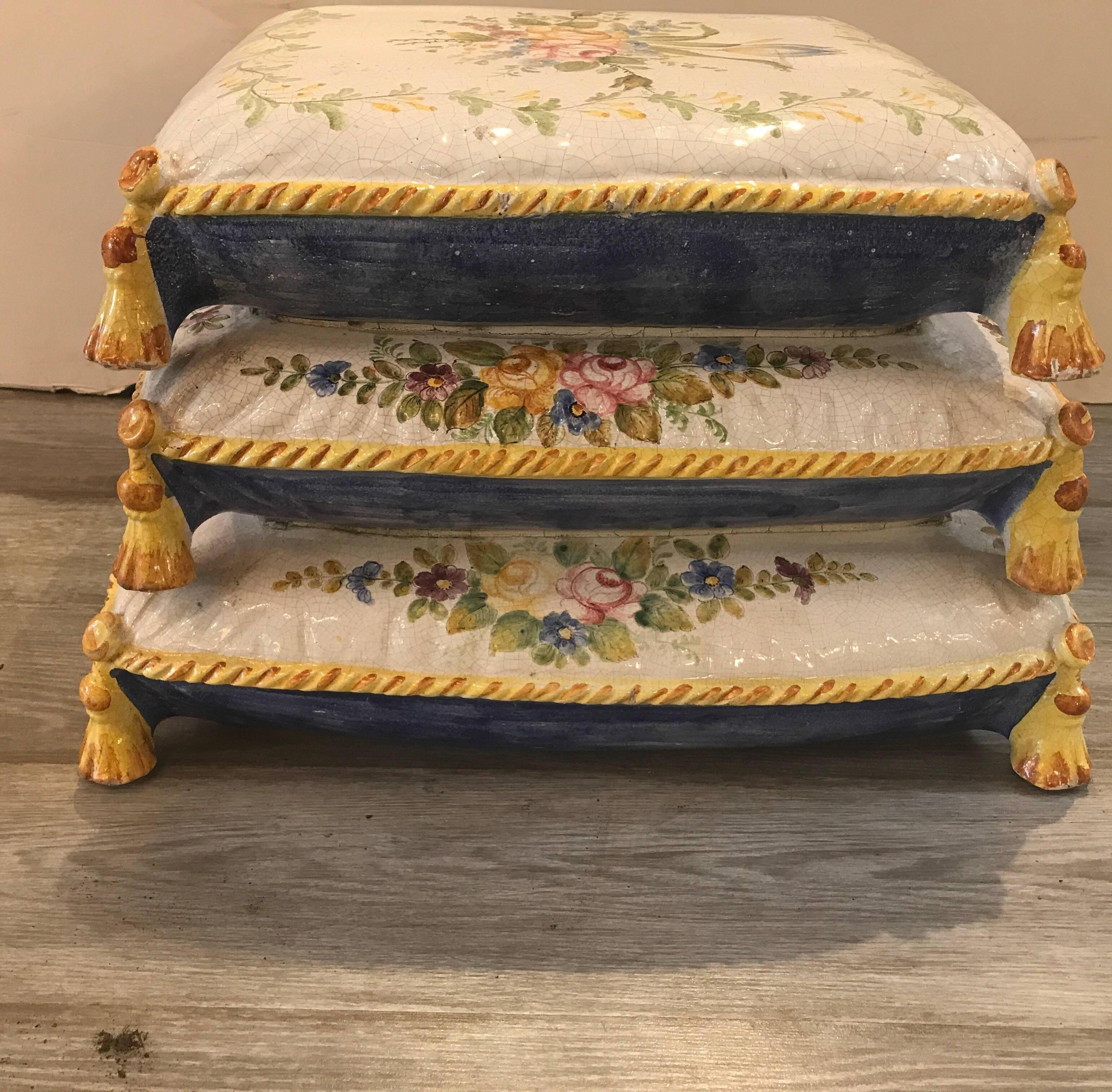 Whimsical hand-painted garden seat in the form of pillows. The painted floral decoration on the top and sides with yellow cording and tassels at the corners.