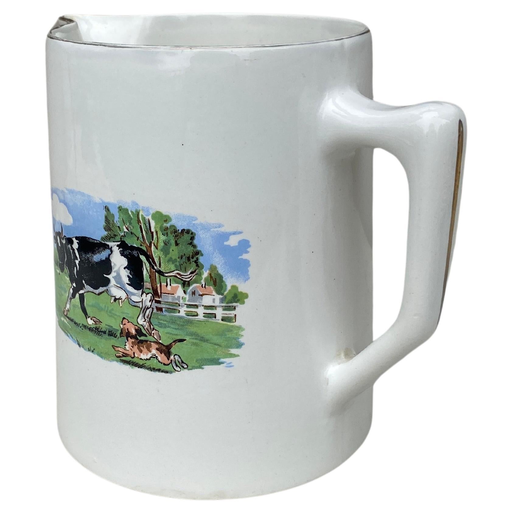 French Faience Pitcher Cow signed Digoin Sarreguemines Circa 1930.The scene represent a cow playing with a dog in a field.