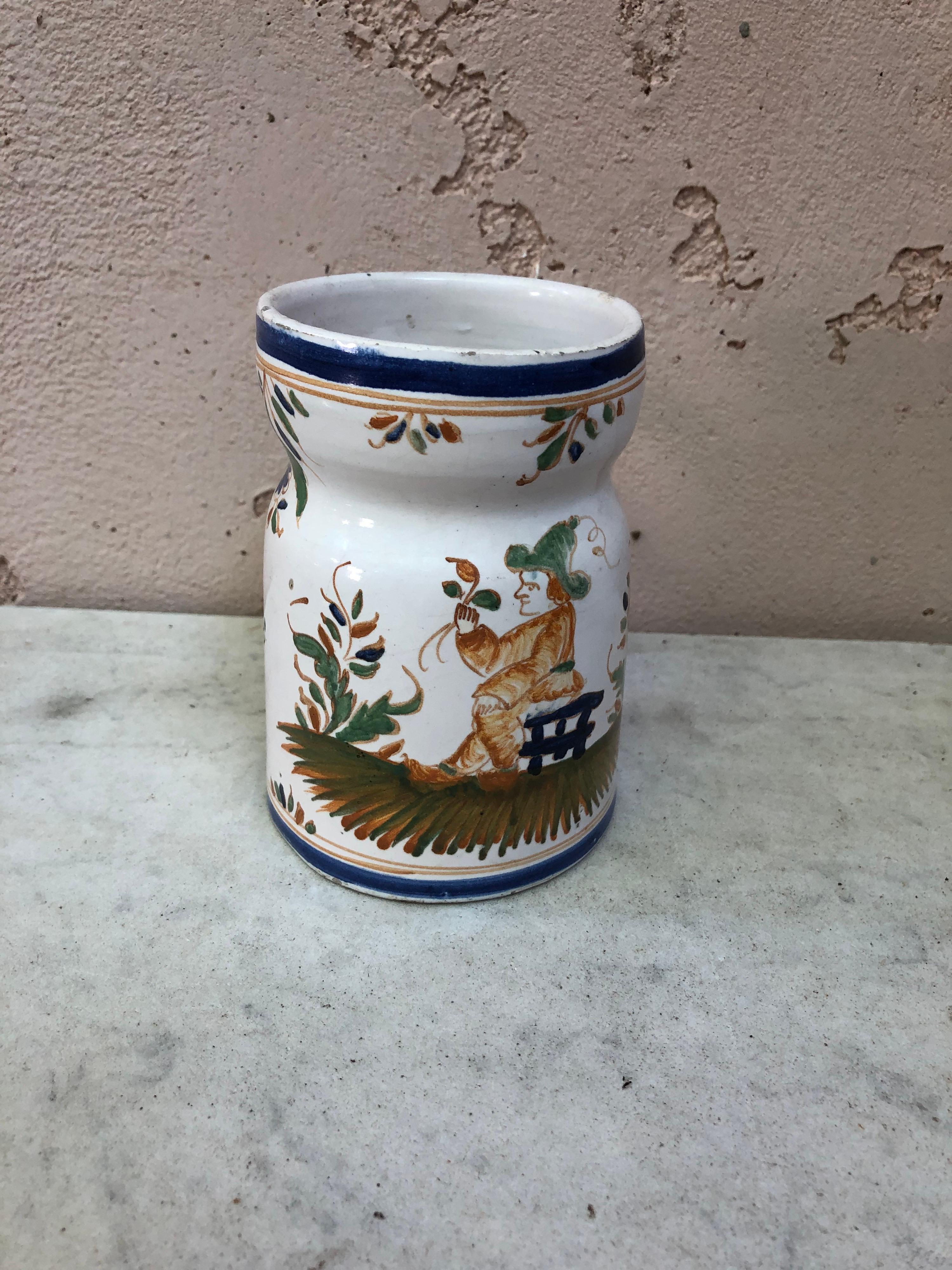 Pichet rustique en faïence française avec des peintures florales et un homme assis sur une clôture, vers 1920.
Moustiers Style.