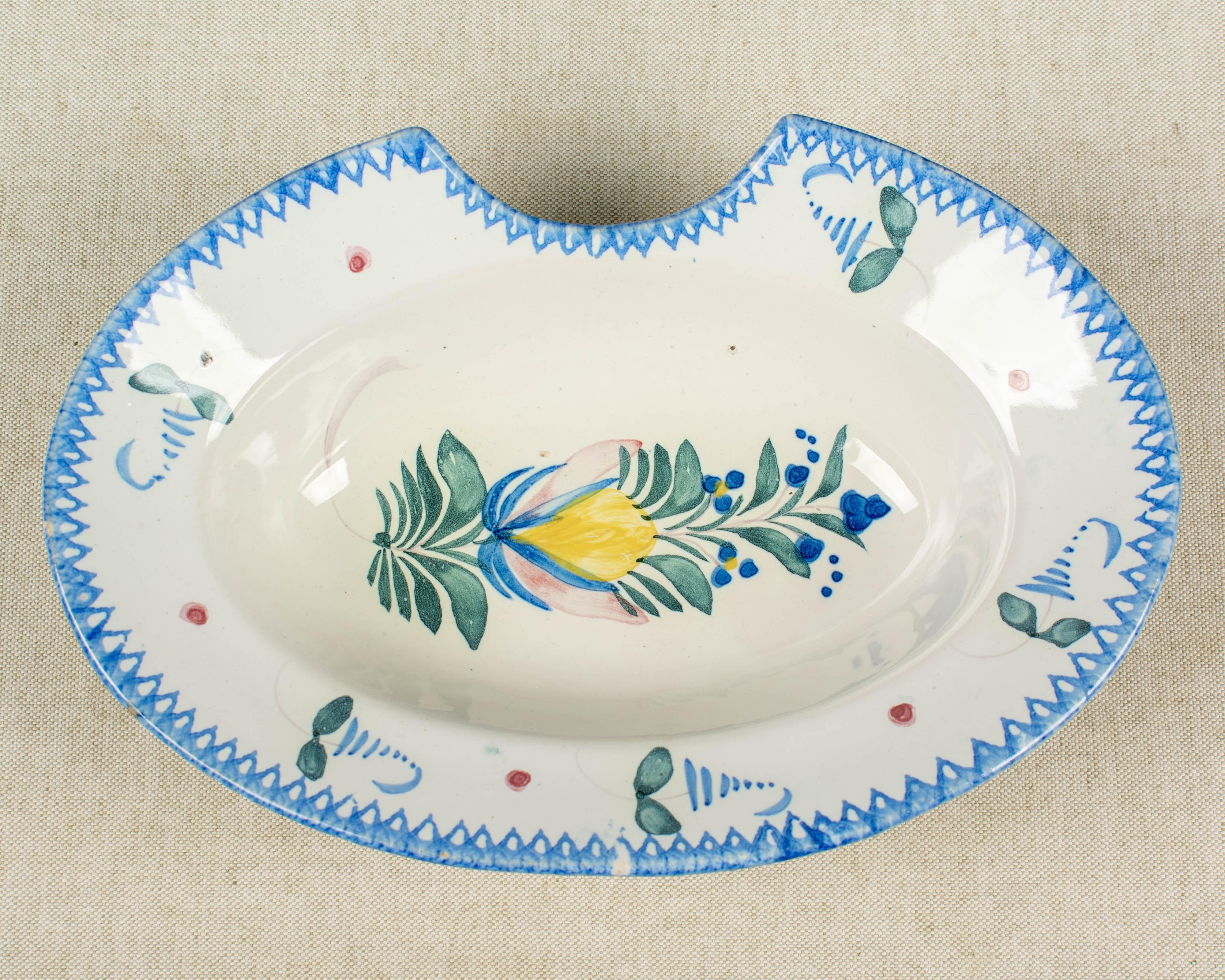 A French faience shaving bowl with hand-painted decoration in blue, green, yellow and pink. Rope on back for hanging.