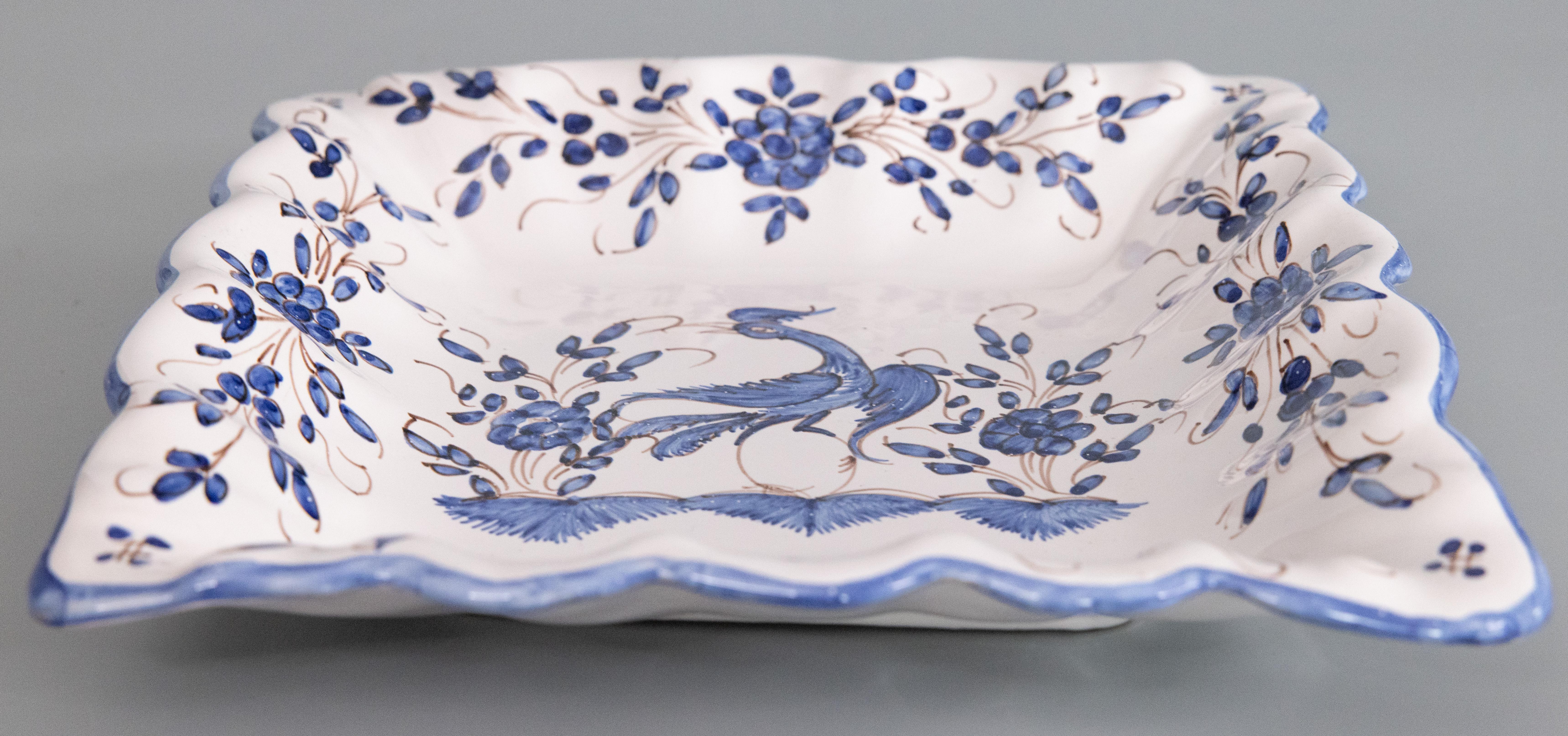 A gorgeous mid-20th century French Moustiers faience square plate or shallow bowl. Hand painted maker's mark on reverse. This beautiful plate is hand painted with a bird and floral design and charming ruffled edge. It would be lovely displayed with