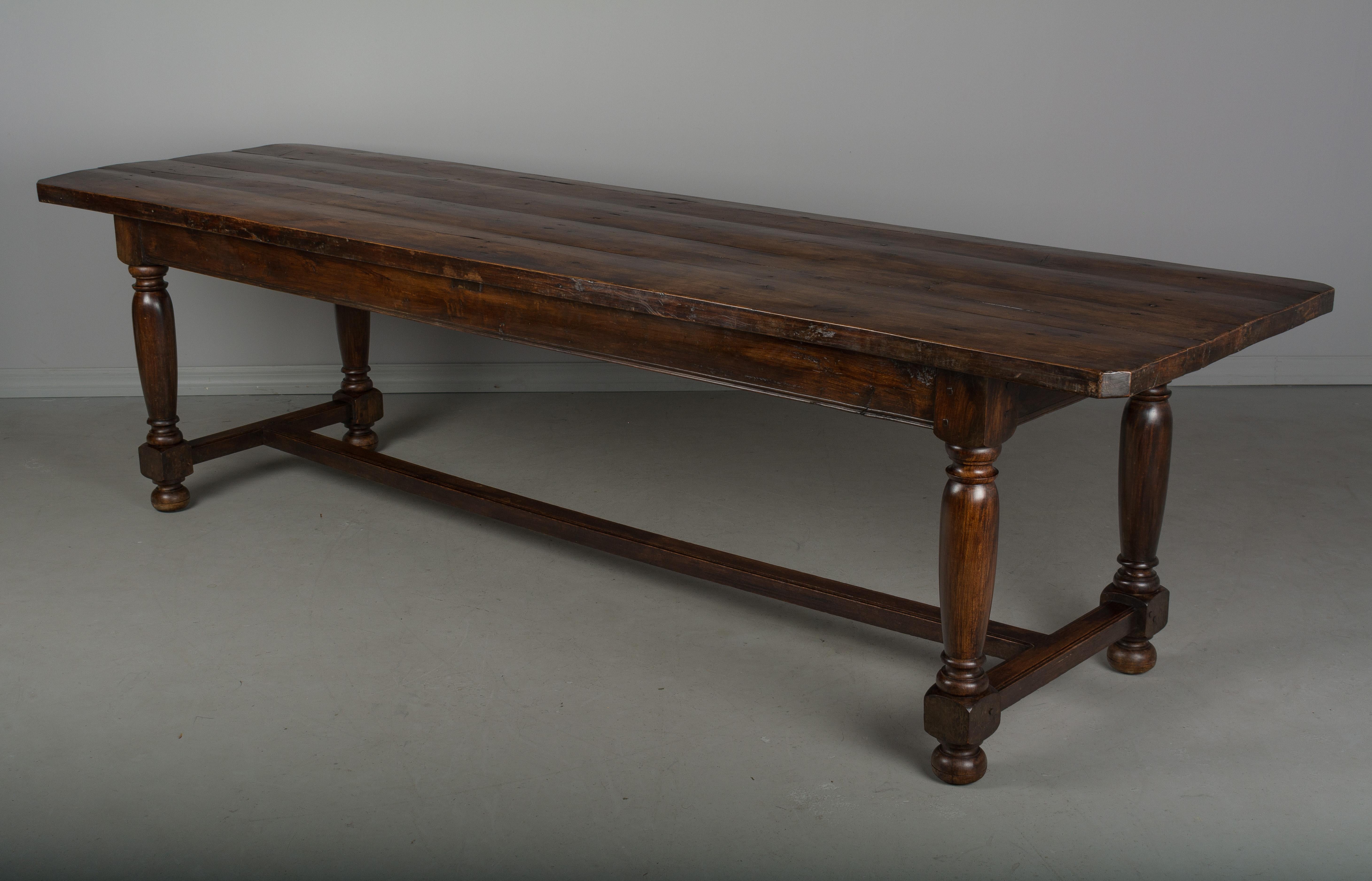A long French country farm table made of solid beechwood with turned legs and stretcher. A heavy, sturdy table of excellent quality, using pegged construction. The top is made of four planks of 1-1/2 inch thick solid beechwood. Waxed patina. A