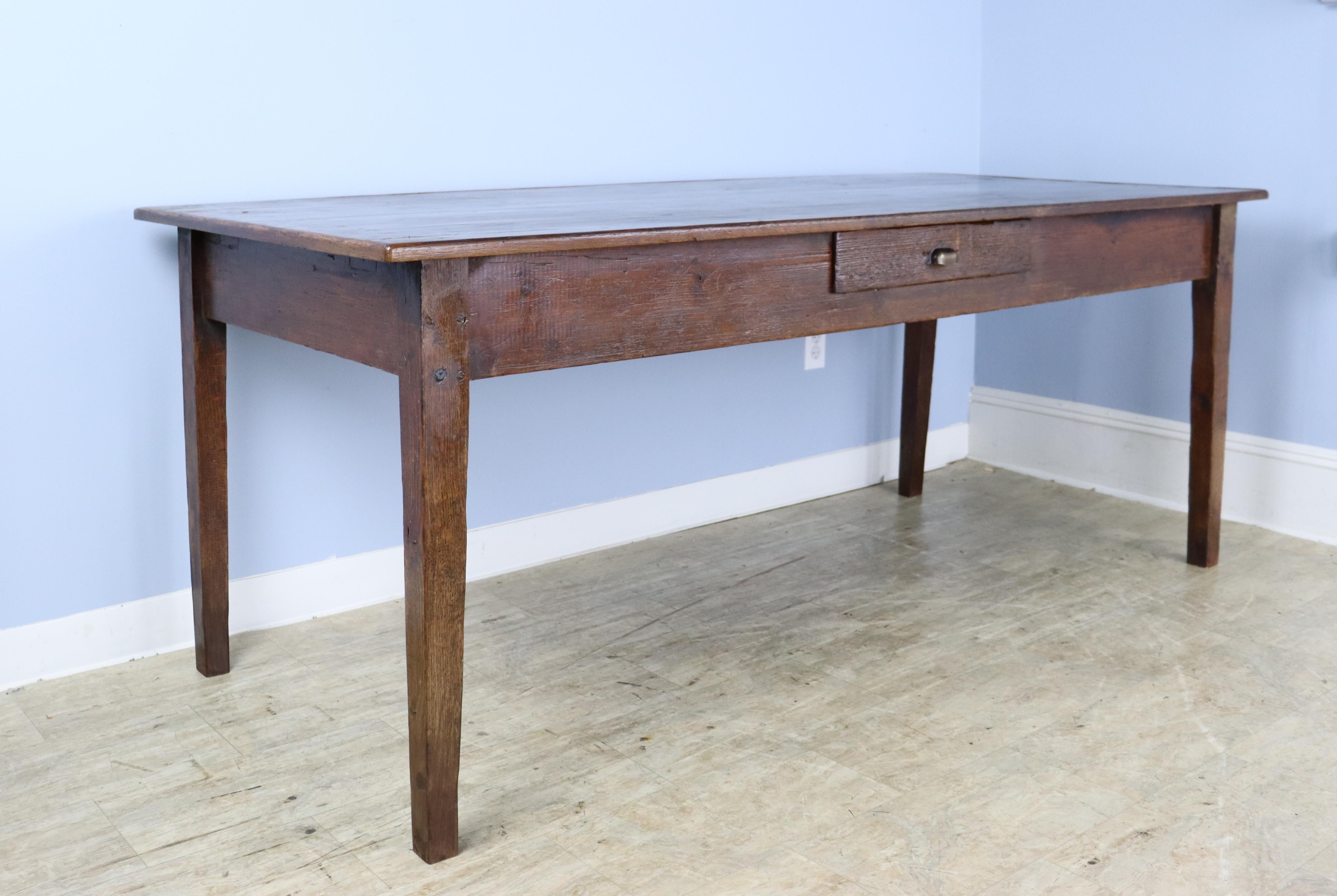 A well proportioned farm table with a chestnut base and a pine top with a decorative wooden edge. The top is in good antique condition and has nice color grain and patina. The apron height of 24.5 inches is good for knees and there are 71.5 inches