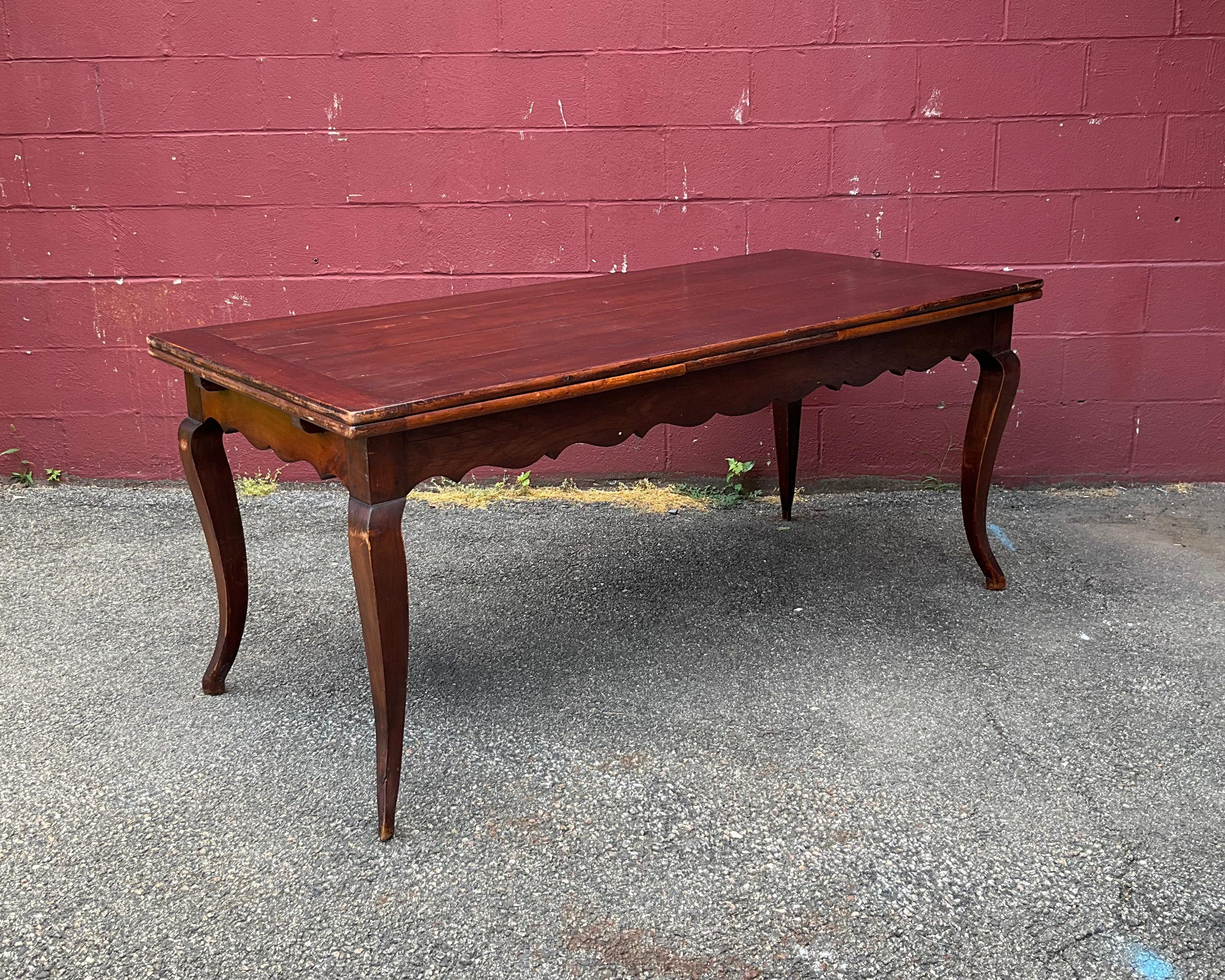 This rustic yet elegant French farm table features two built in leaves, gracefully curved legs and a scalloped apron. When closed, the table is 67¾ inches in length but can extend to 93¼ inches when using the leaves. Hailing from the early 20th