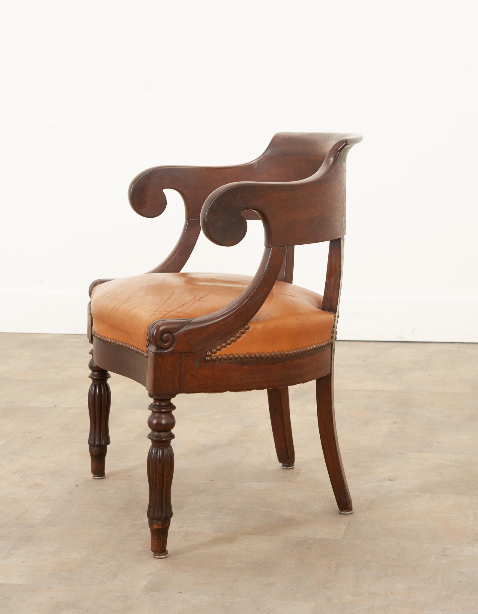 Ce fauteuil de bureau de style Charles X est de forme classique et présente une assise en cuir caramel merveilleusement usée. Le cadre du dossier incurvé en acajou présente une touche sophistiquée de détails sculptés à la main sur les bras et les
