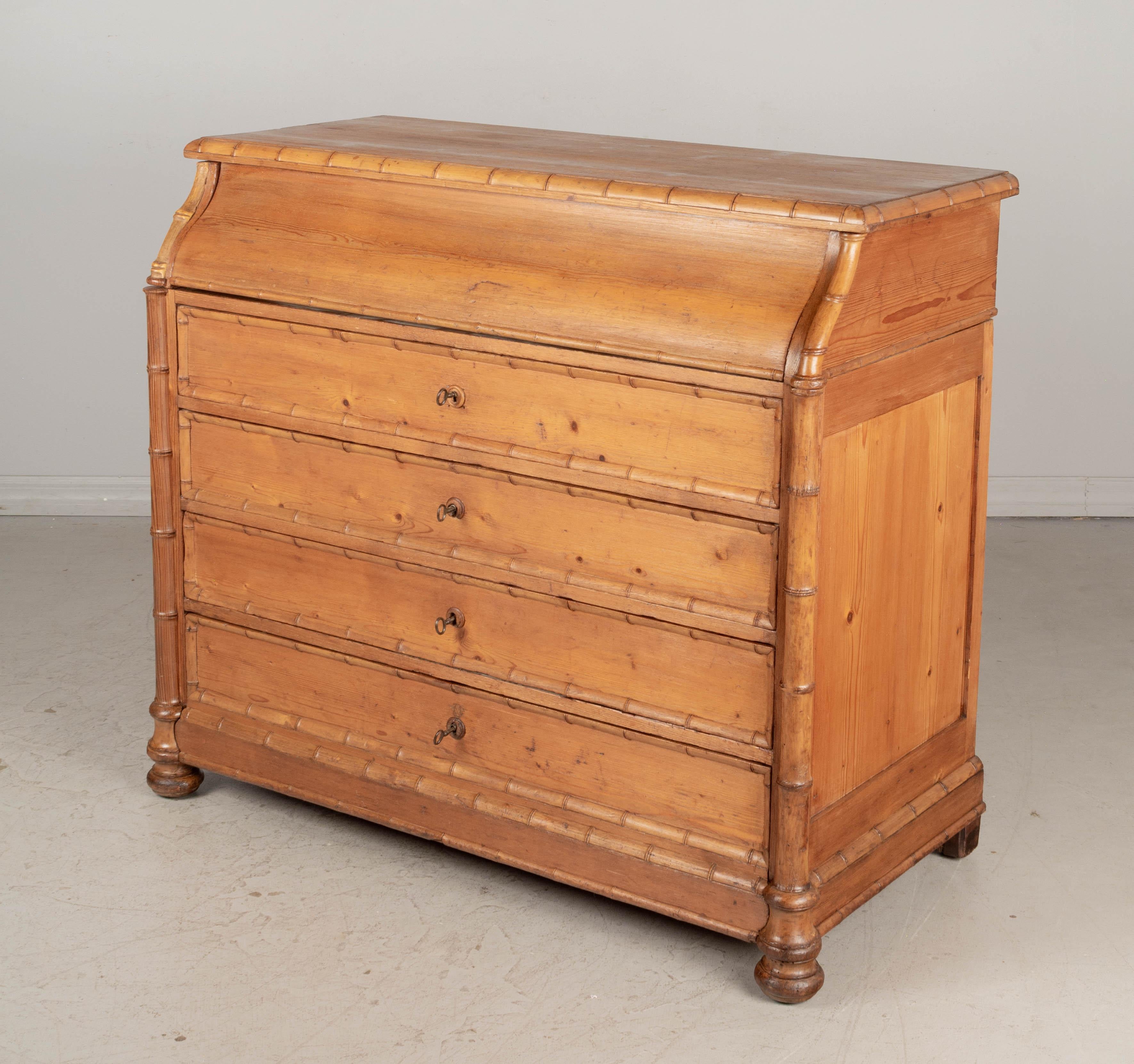 An early 20th century French faux bamboo commode de toilette, or dresser with a pull-out marble top vanity and mirror. Made of pine with cherry wood faux bamboo trim. Four dovetailed drawers, each with working lock and key. The top hinges open and