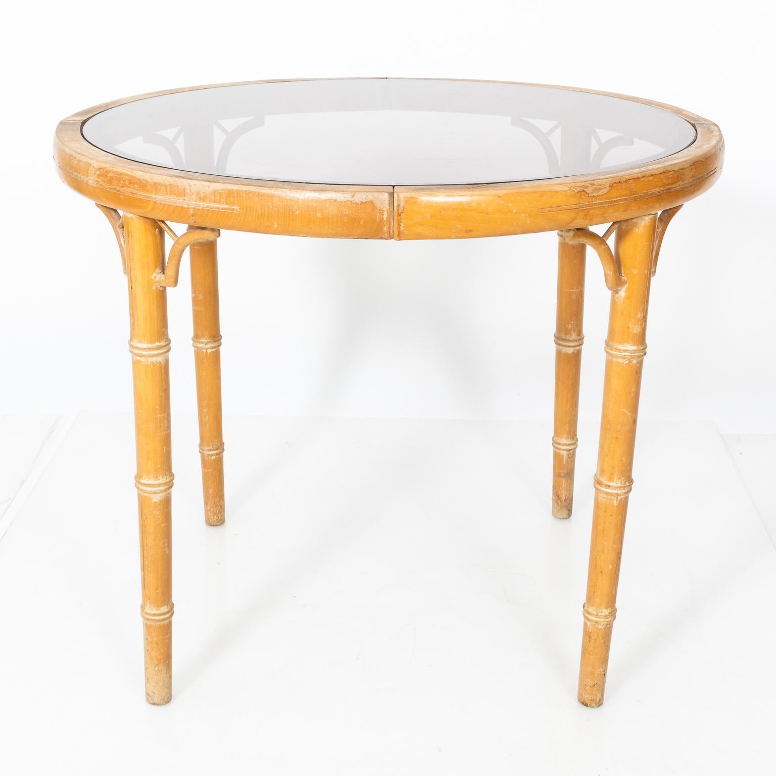 French faux bamboo table with smokey glass top, circa 19th century. Please note of wear consistent with age including scratches and wear to the finish. There is also a crack on the rim of the tabletop.