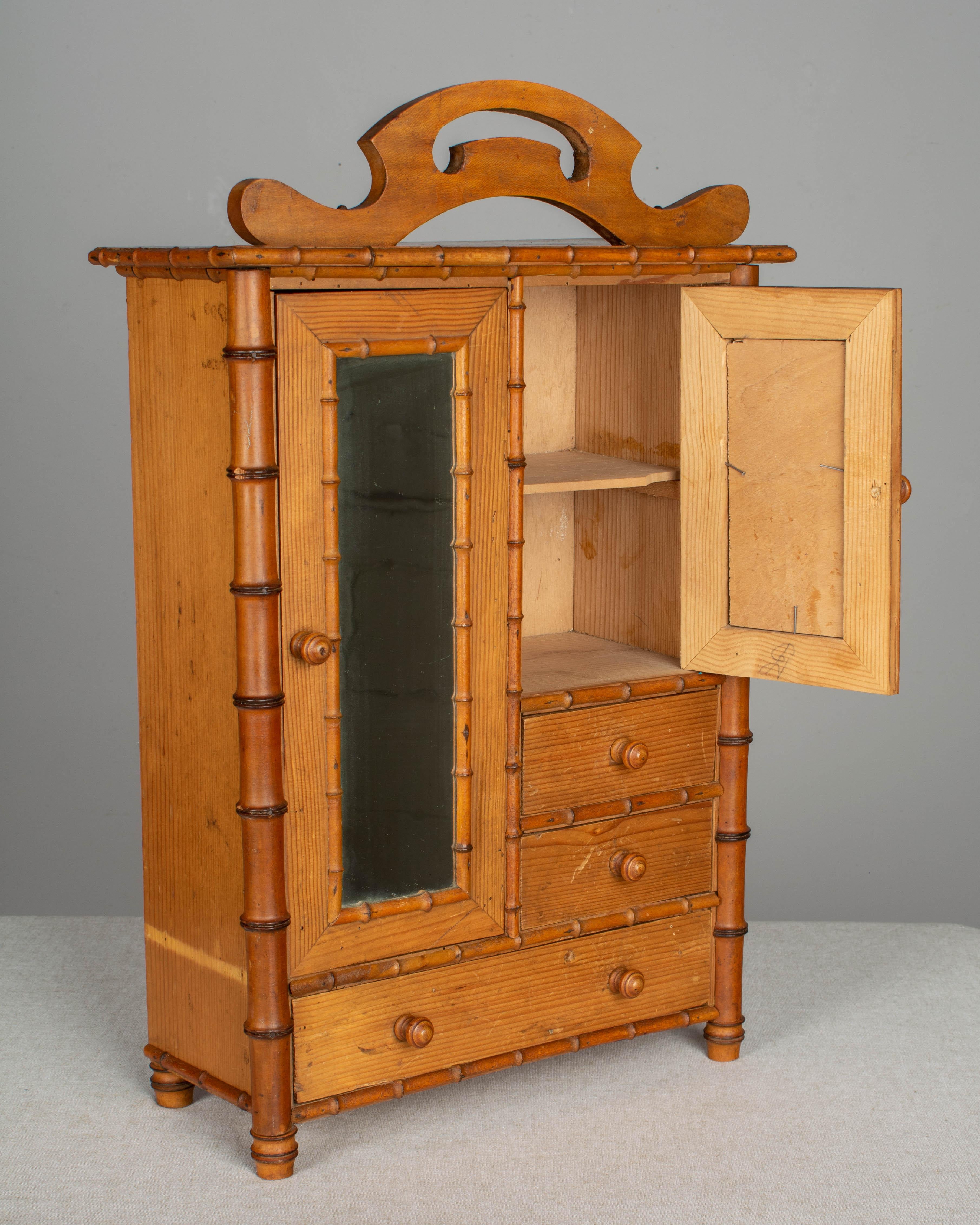 A French faux bamboo doll furniture armoire made of cherry and pine. In good condition with two pieces of trim missing. The back foot was replaced with a cork and the smaller mirror has been replaced.