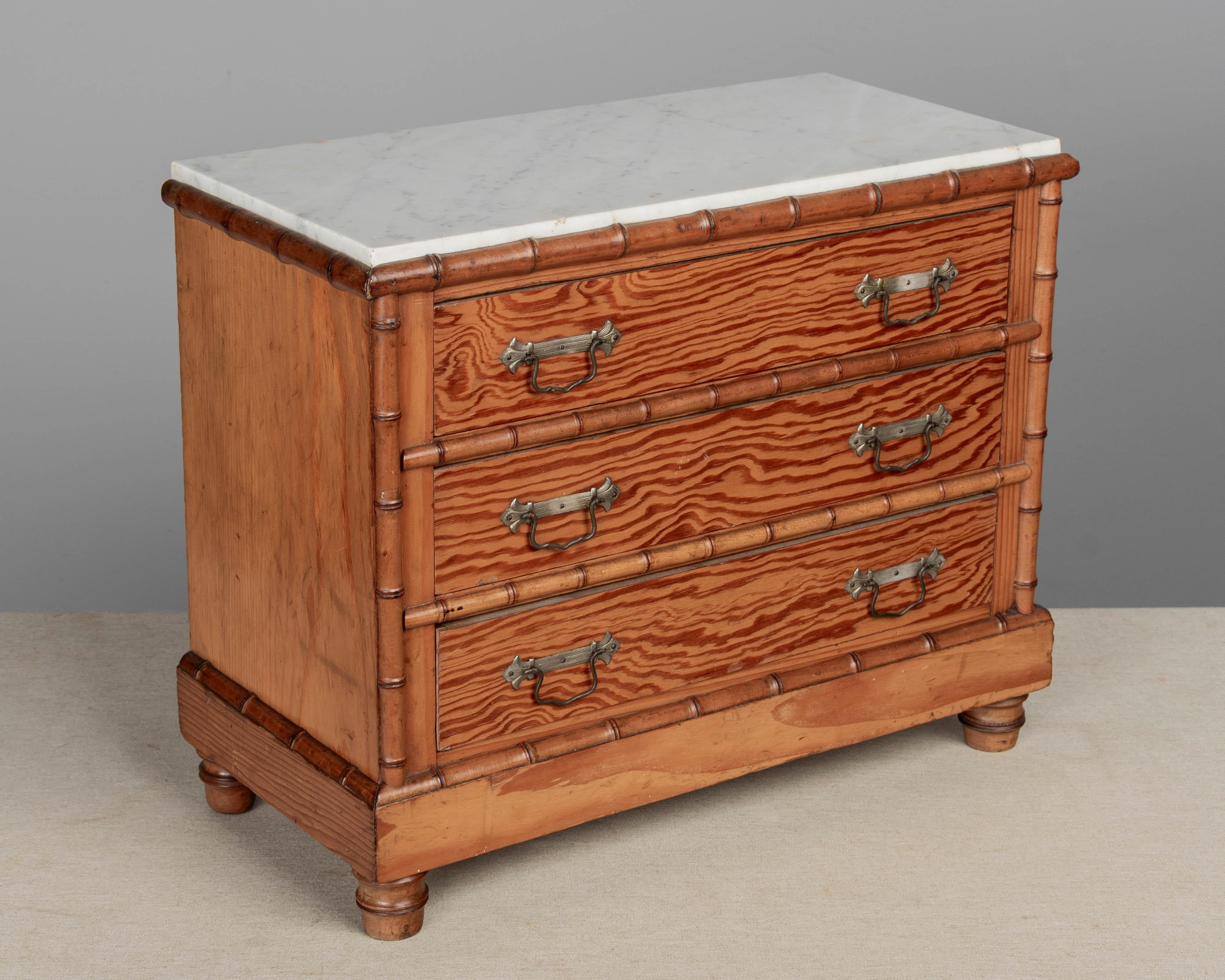 A French faux bamboo miniature marble top commode made of pine and cherry woods. Three drawers with brass pulls. Nicely detailed with turned cherry trim and feet. Perfect for storing treasured objects or for use as a jewelry box or men's valet.
