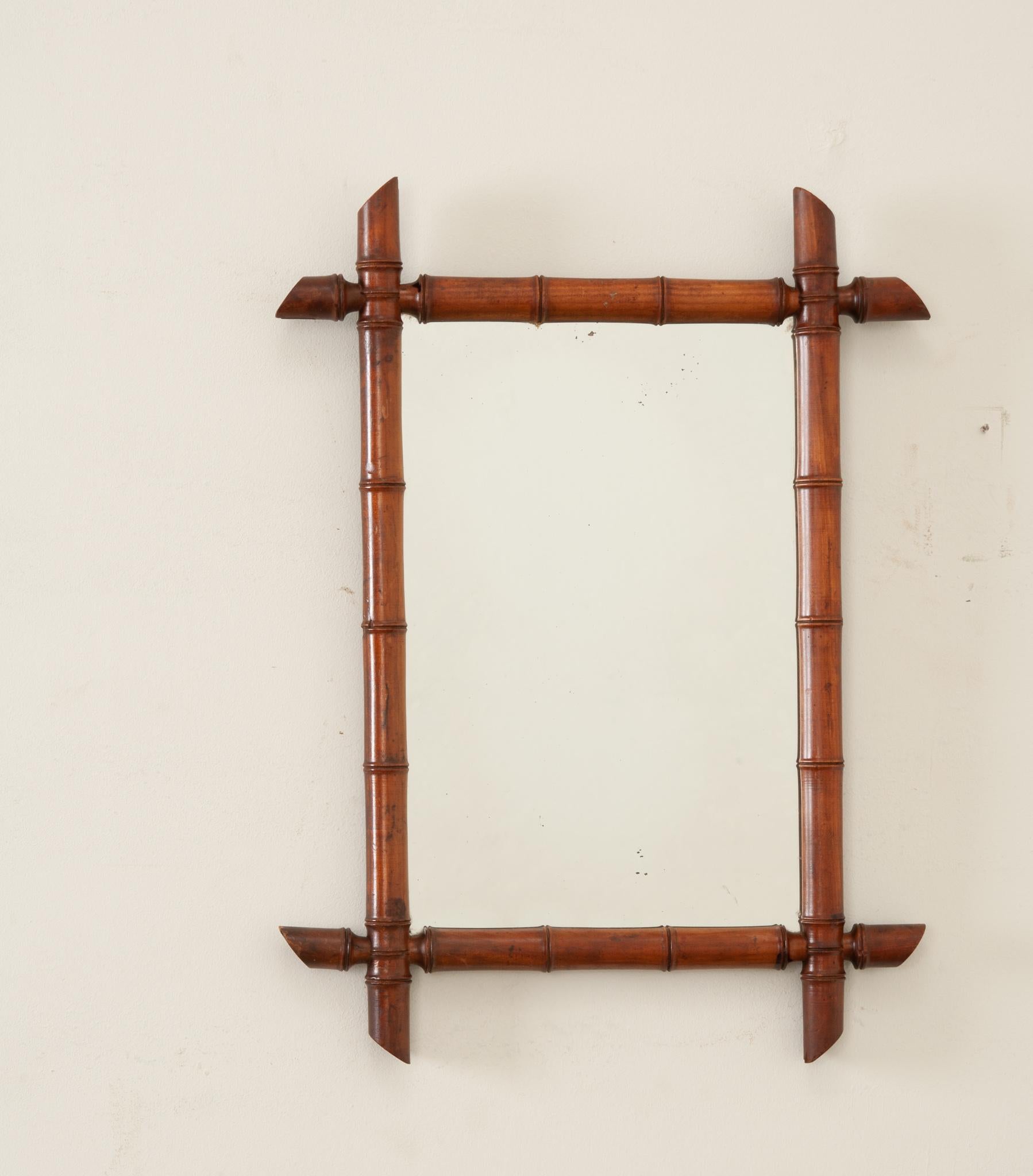 A delightful turned wood, faux bamboo mirror from early 20th Century France. The mirror’s wood frame has been artfully turned to a stylized bamboo motif. The mirrored glass is original to the antique with some foxing present. While the mirror is