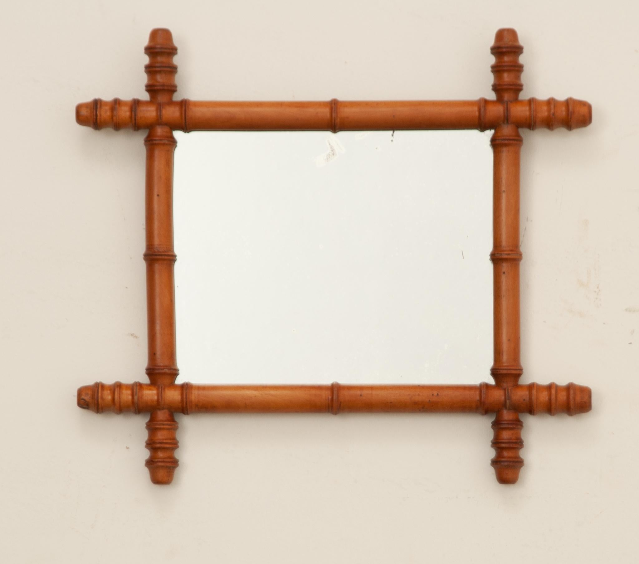 Ein reizvoller Spiegel aus gedrechseltem Holz und Bambusimitat aus dem Frankreich des frühen 20. Jahrhunderts. Der Holzrahmen des Spiegels wurde kunstvoll zu einem stilisierten Bambusmotiv gedreht. Das verspiegelte Glas ist original auf die antike