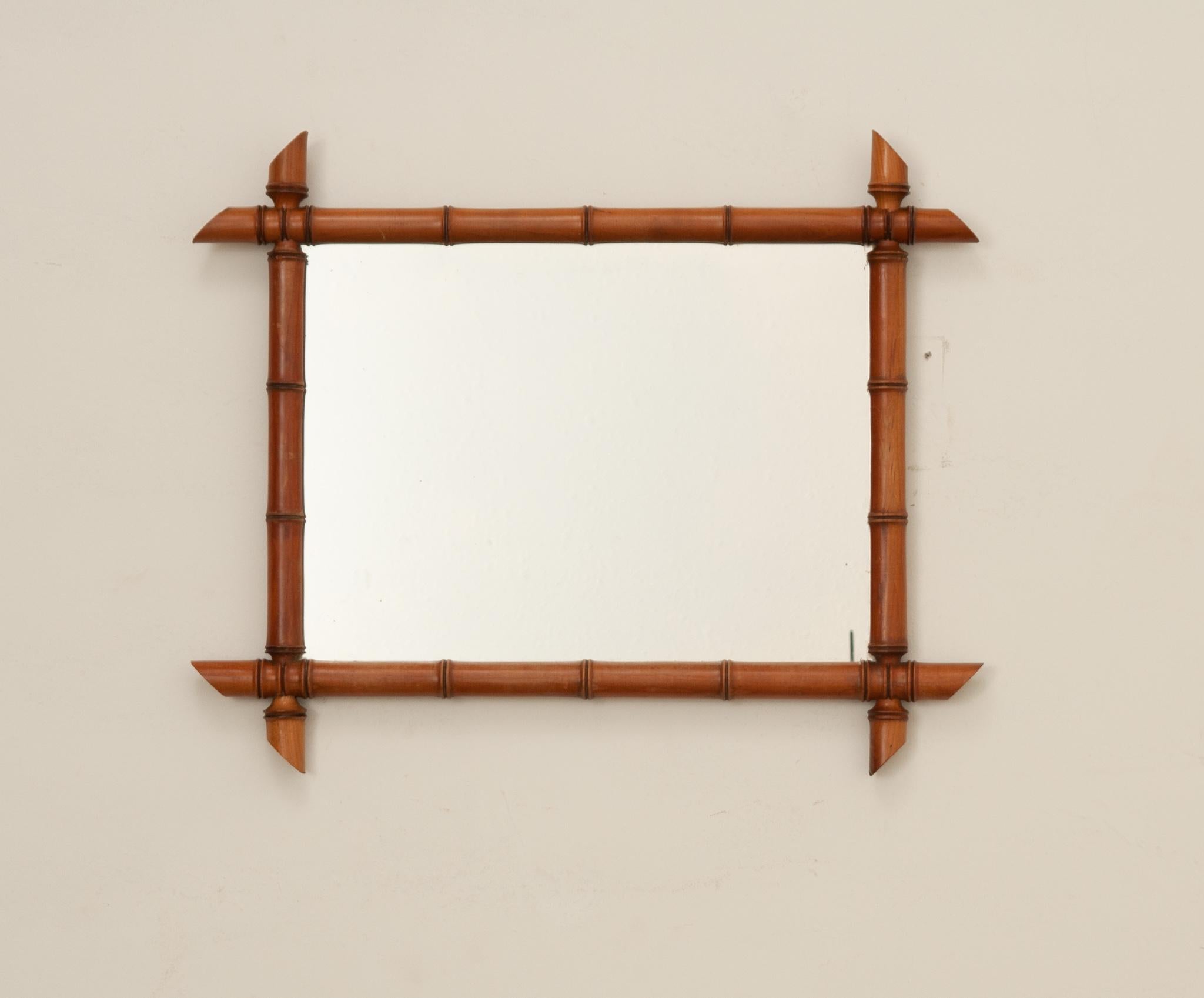 A delightful turned wood, faux bamboo mirror from early 20th Century France. The mirror’s wood frame has been artfully turned to a stylized bamboo motif. The mirrored glass is original to the antique with some foxing present. While the mirror is