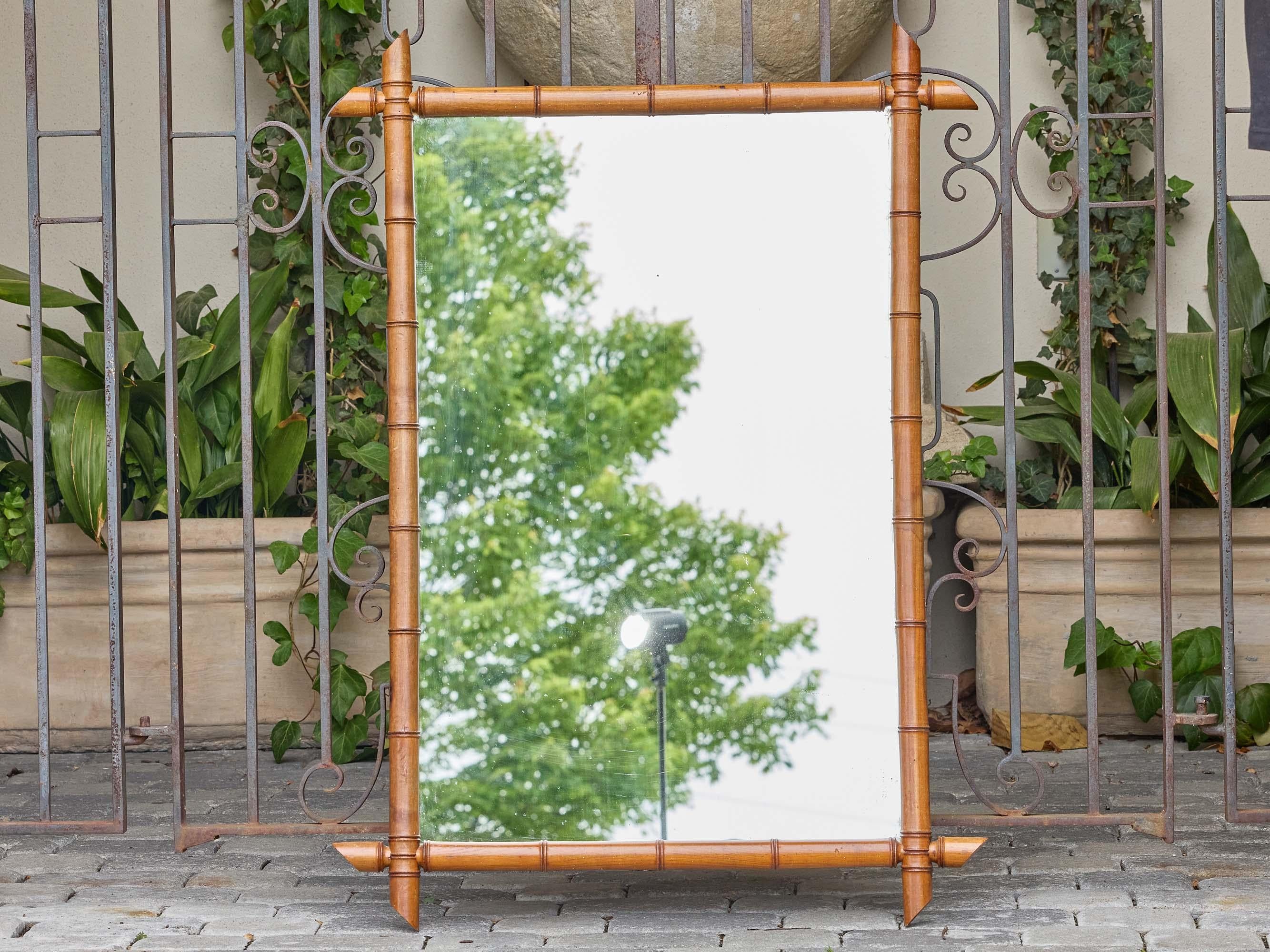 Este espejo de pared francés de principios del siglo XX presenta un llamativo marco de imitación de bambú en un cálido tono marrón dorado, probablemente de madera de frutal. El diseño imita el aspecto segmentado del bambú auténtico, con detalles
