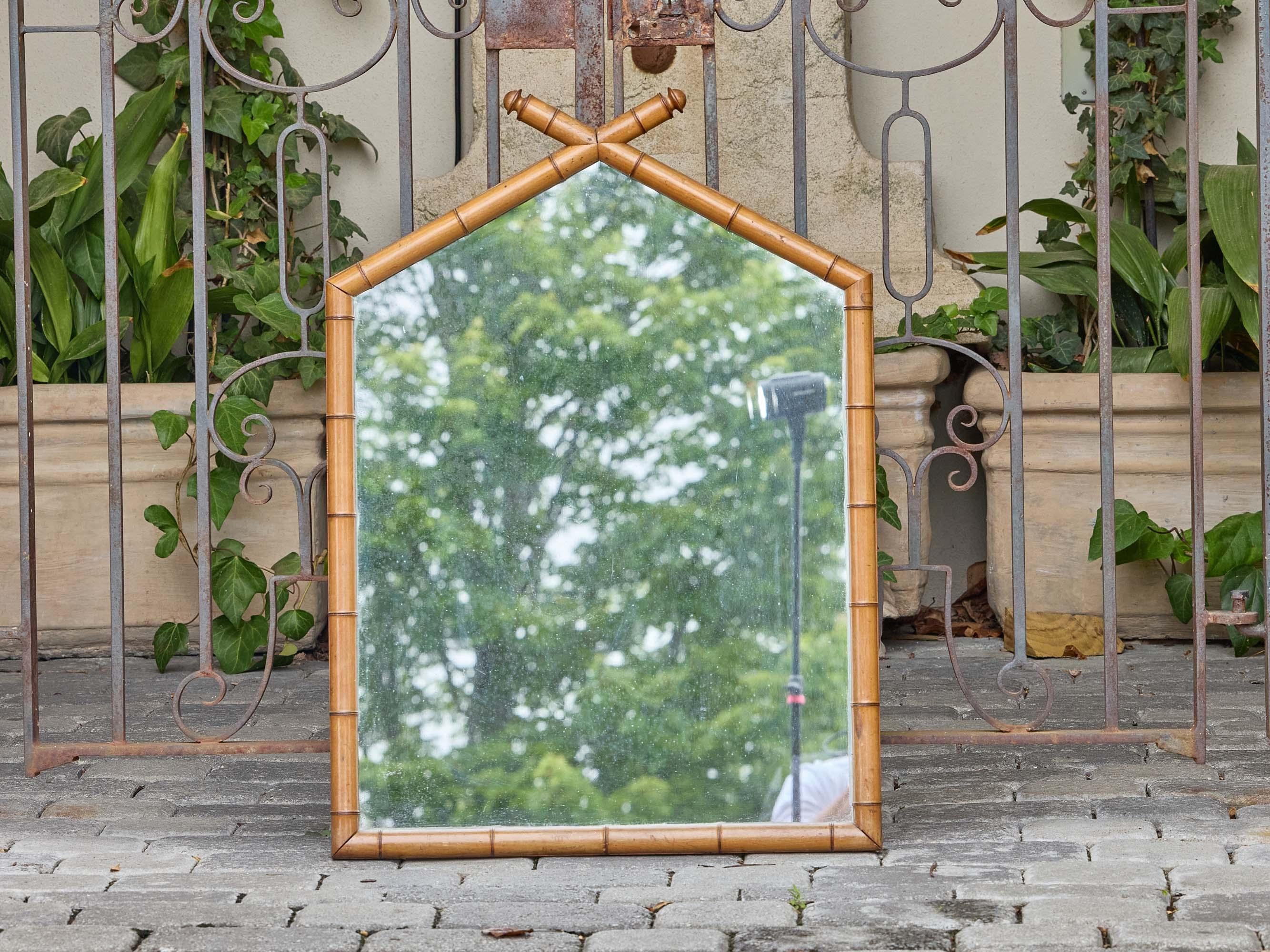 Questo specchio francese vintage è incorniciato in legno intagliato con una finitura in finto bambù dai toni caldi, che gli conferisce il fascino naturale dei mobili in bambù inglesi e continentali dell'inizio del XX secolo. La silhouette unica