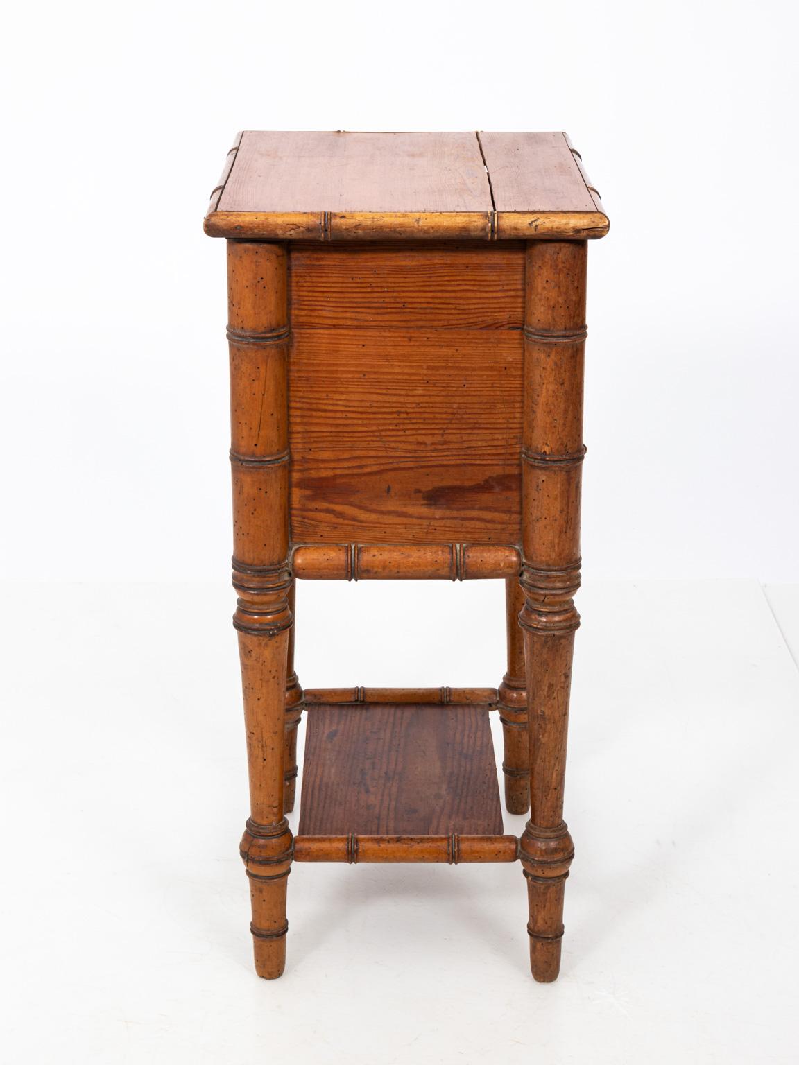 French faux bamboo night stand or side table made of long-leaf pinewood with one drawer, a lower cabinet, and bottom shelf, circa 19th century. The piece also features ring turned legs. Please note of wear consistent with age including a crack on