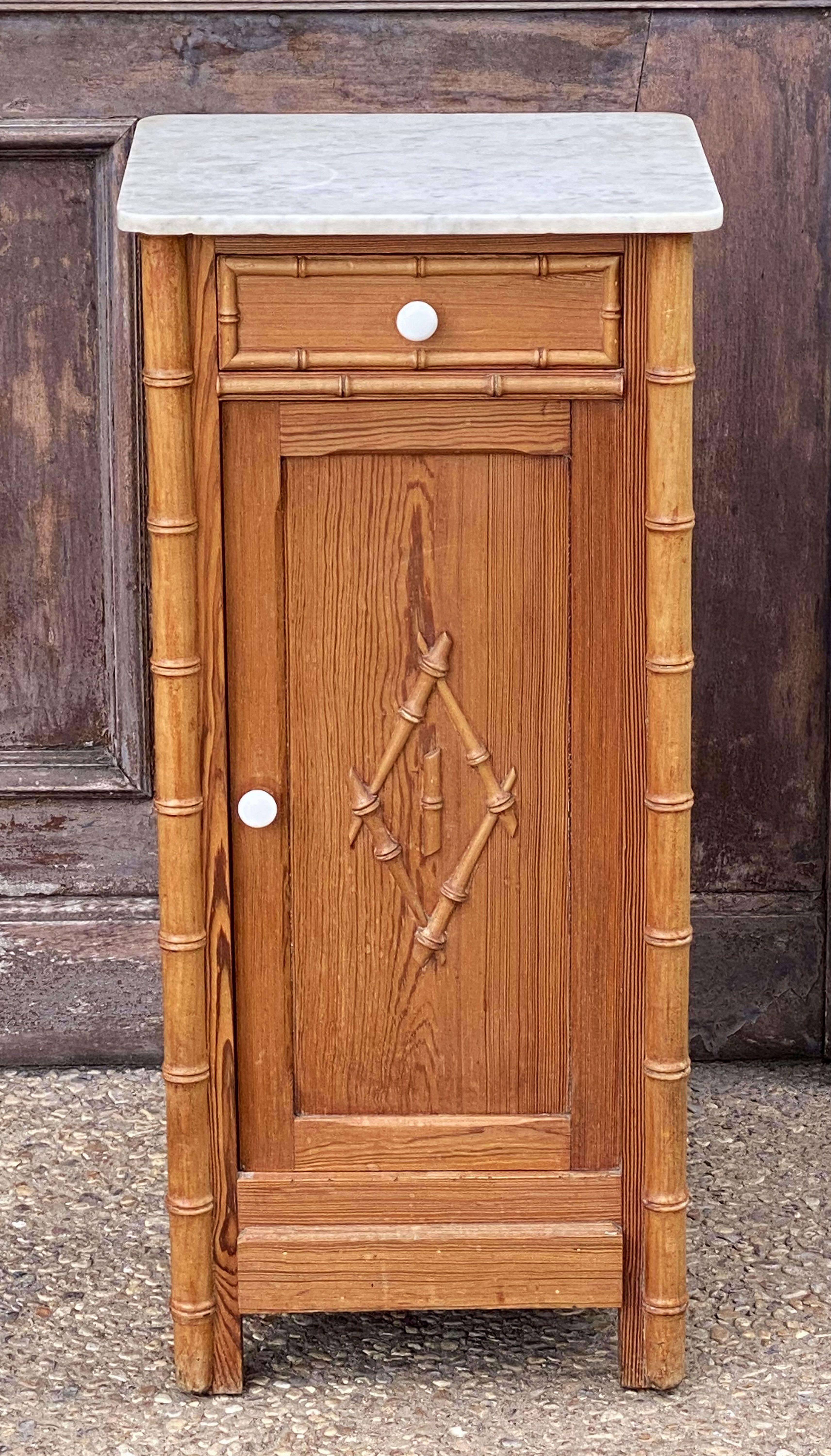 A handsome French faux bamboo nightstand (or commode) of long-leaf pine, featuring a white marble top with grey accents, over a frieze with drawer and cabinet door. The cabinet door opening to an interior with one shelf.
The whole accentuated by a