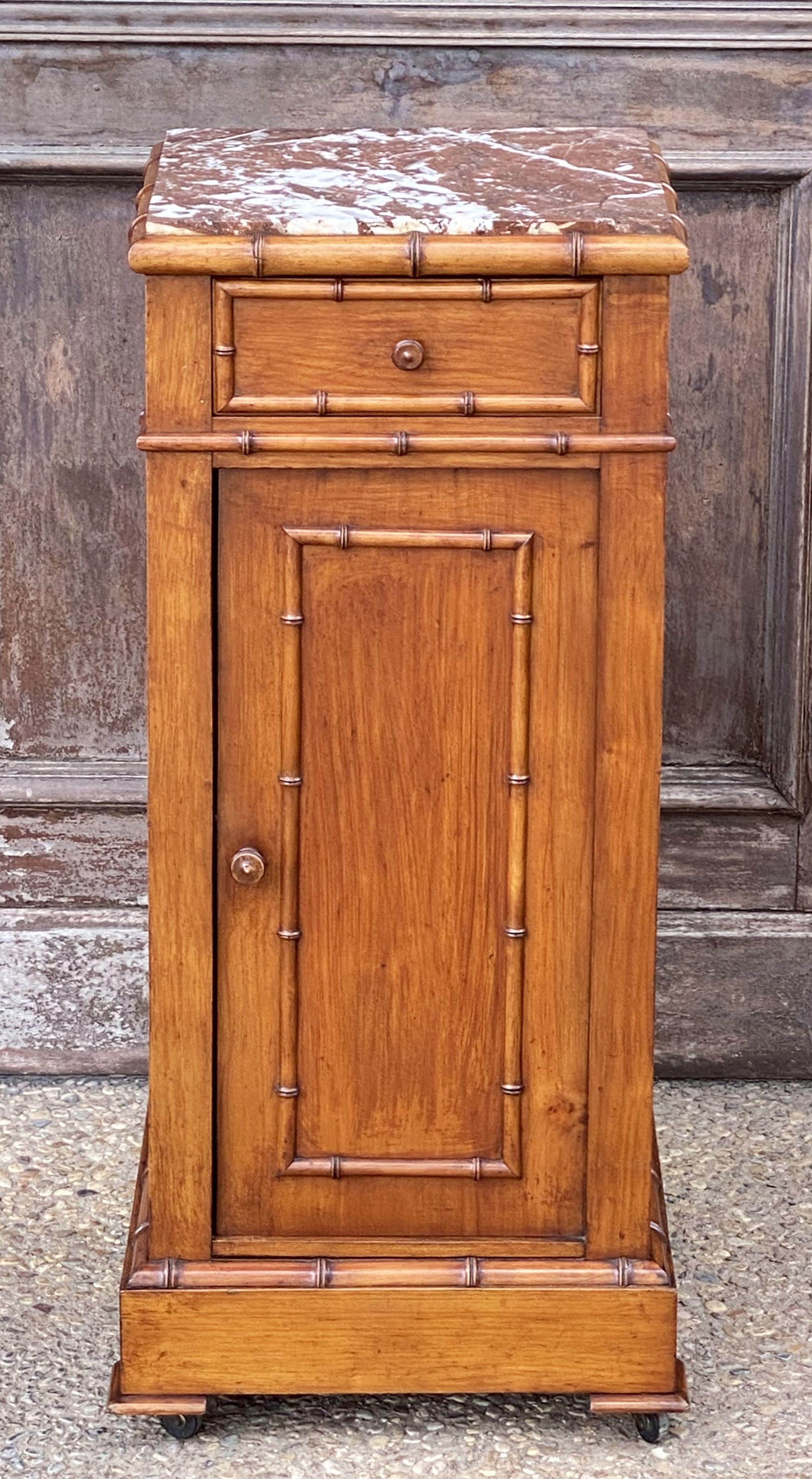 A handsome French faux bamboo nightstand (or commode) of long-leaf pine with a rich walnut stain finish, featuring a mottled red marble top with white and grey accents, over a frieze with drawer and cabinet door. The cabinet door opening to an