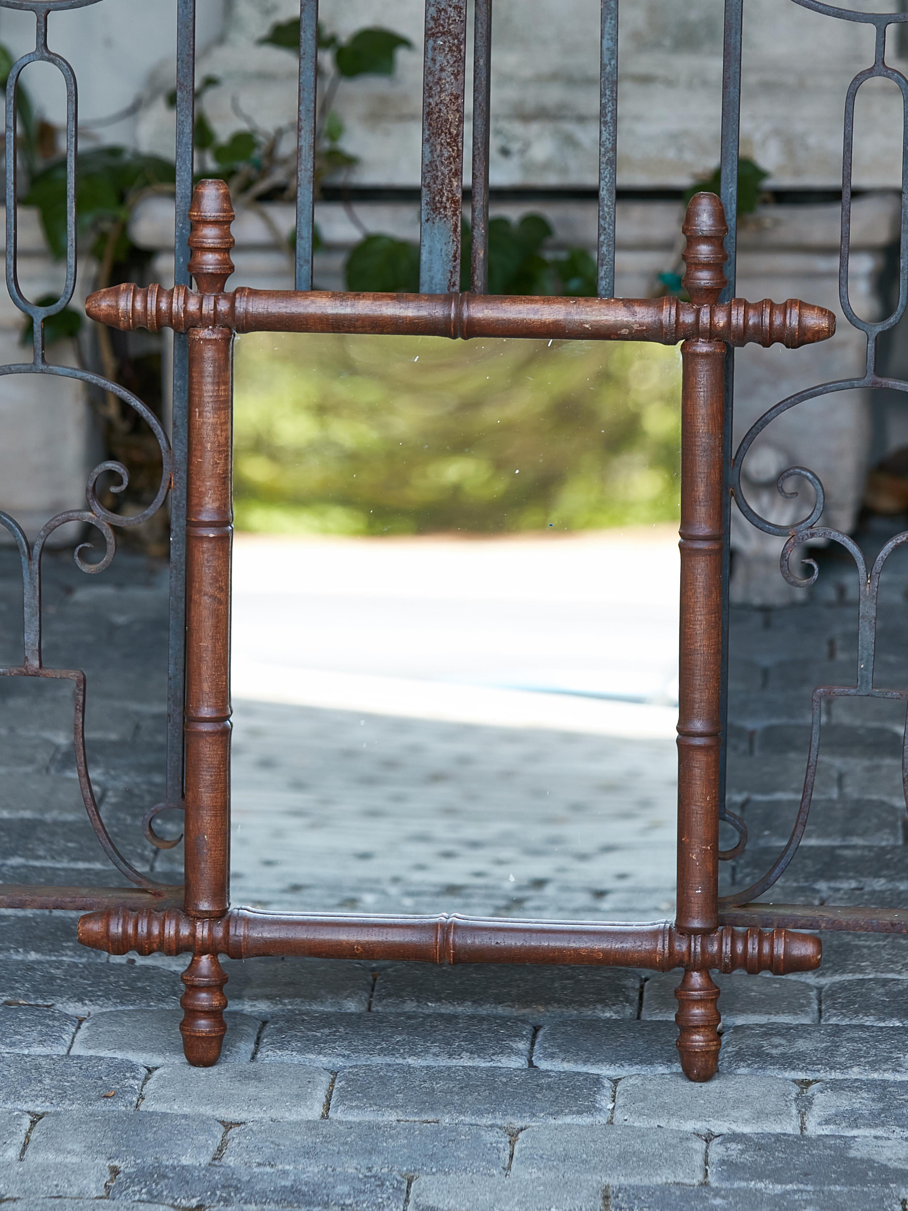 A small French Turn of the Century faux-bamboo mirror from circa 1900 with intersecting corners, reeded accents and rustic character. Charm your space with this small French Turn of the Century faux-bamboo mirror, a rustic treasure hailing from