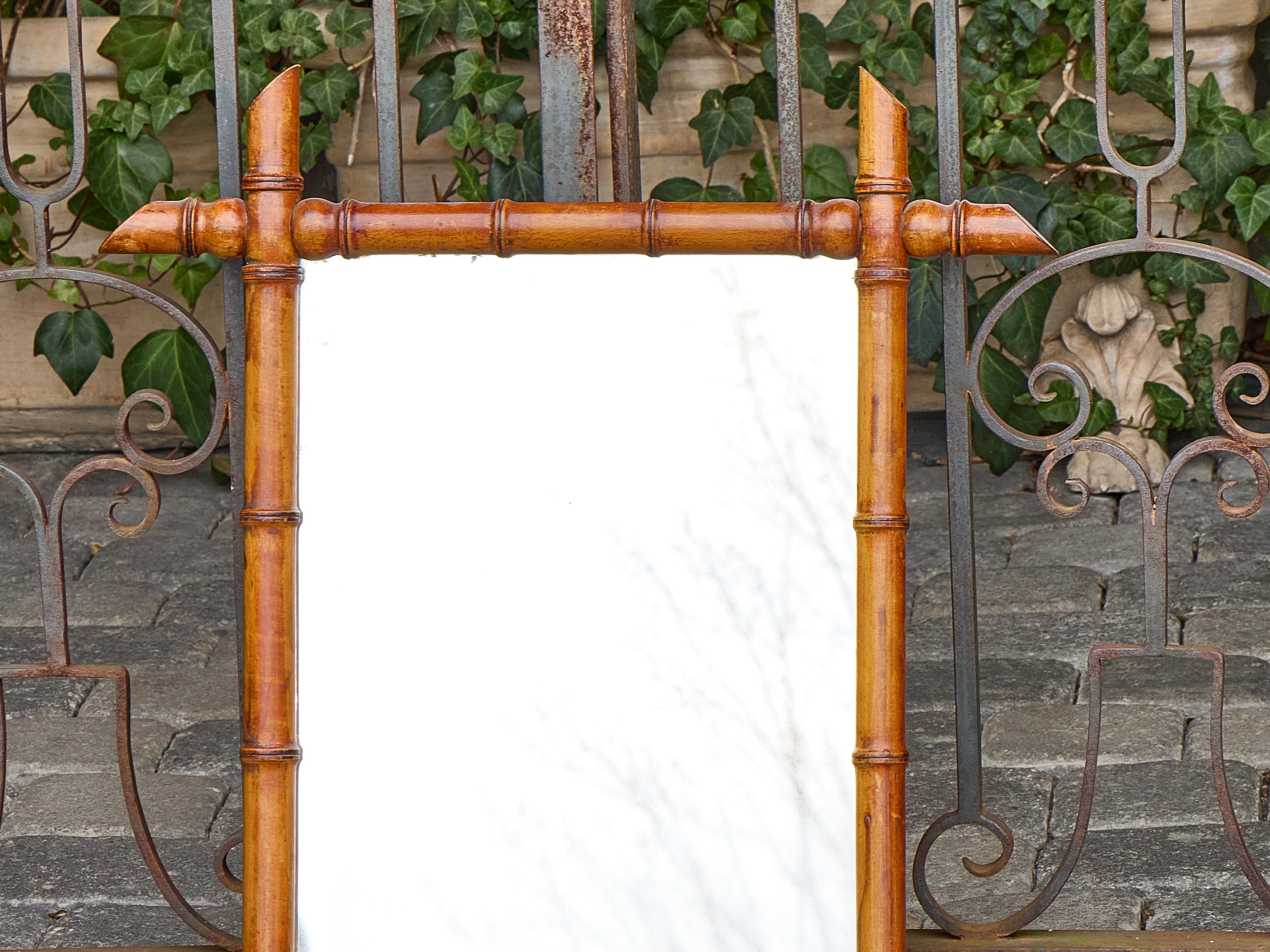 Ce miroir français en faux bambou, datant d'environ 1900, reflète l'attrait durable du design colonial et de campagne avec son cadre sculptural et son ton chaud et mielleux. Fabriqué en bois tourné pour imiter le bambou naturel, le cadre présente