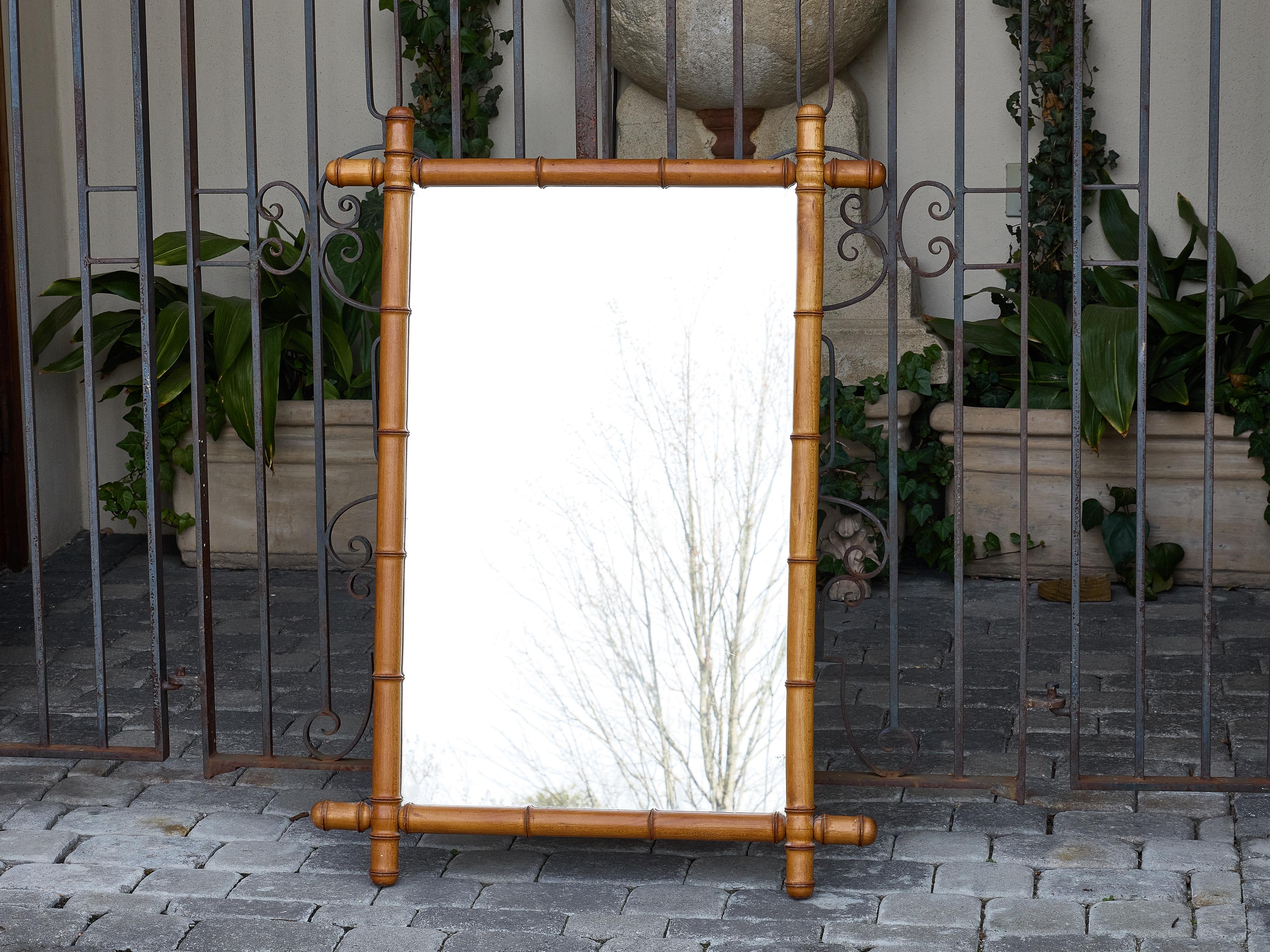 This French faux bamboo mirror from around 1920 captures the casual elegance of the colonial revival aesthetic. Crafted in wood and carved to simulate bamboo, the frame offers the organic, rhythmic look of natural cane while retaining the structural