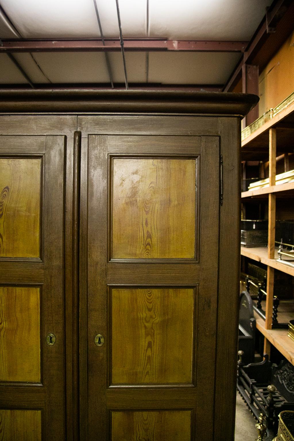 This armoir has exposed double peg construction. The doors each have three recessed panels framed with carved moldings. The entire cupboard is painted to simulate heart pine. The right hand section has three shelves. The left hand section has one